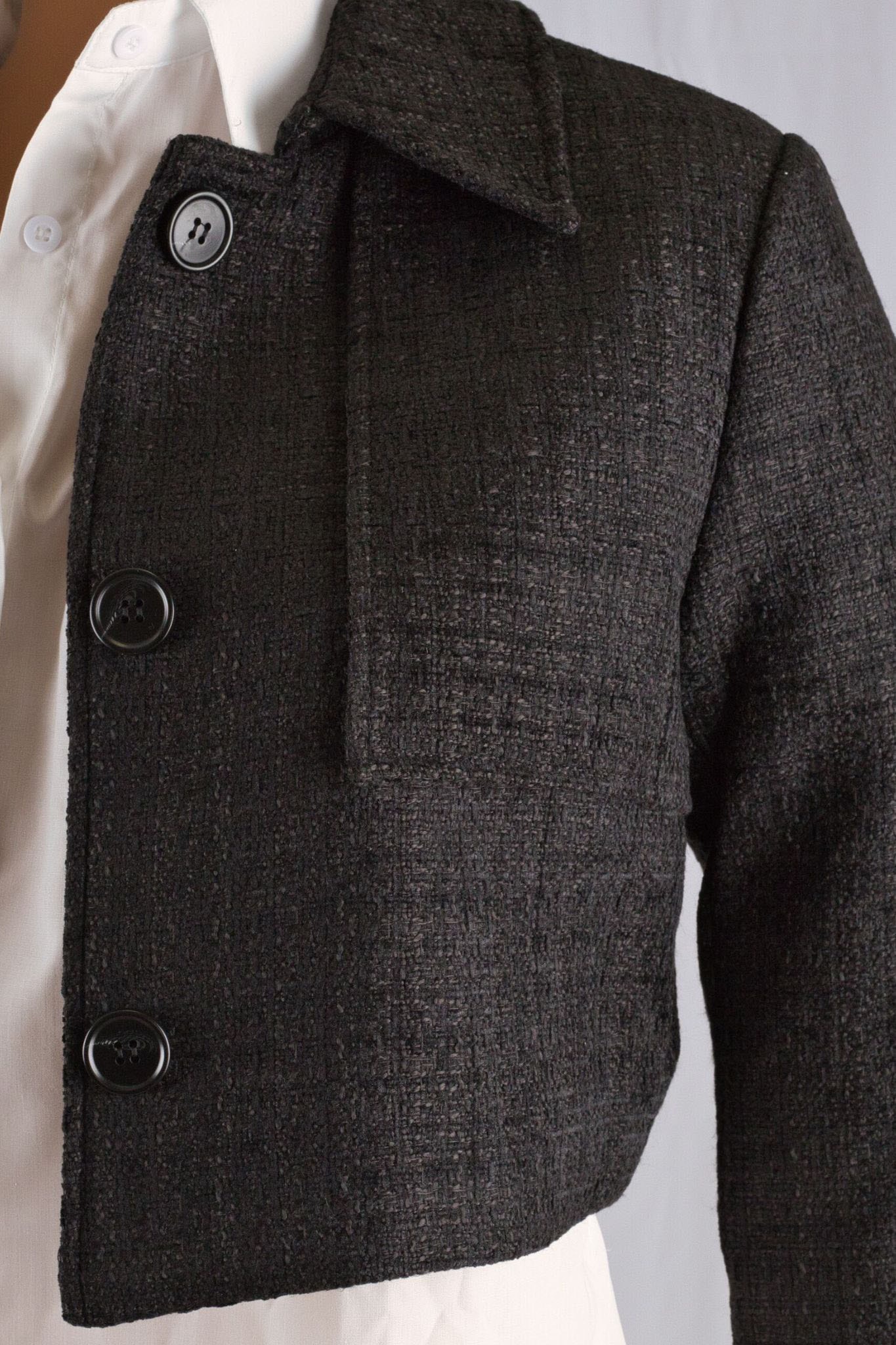 Schwarze Tweedjacke im Cropped-Stil mit Satinfutter, perfekt für eine schlanke und elegante Silhouette.