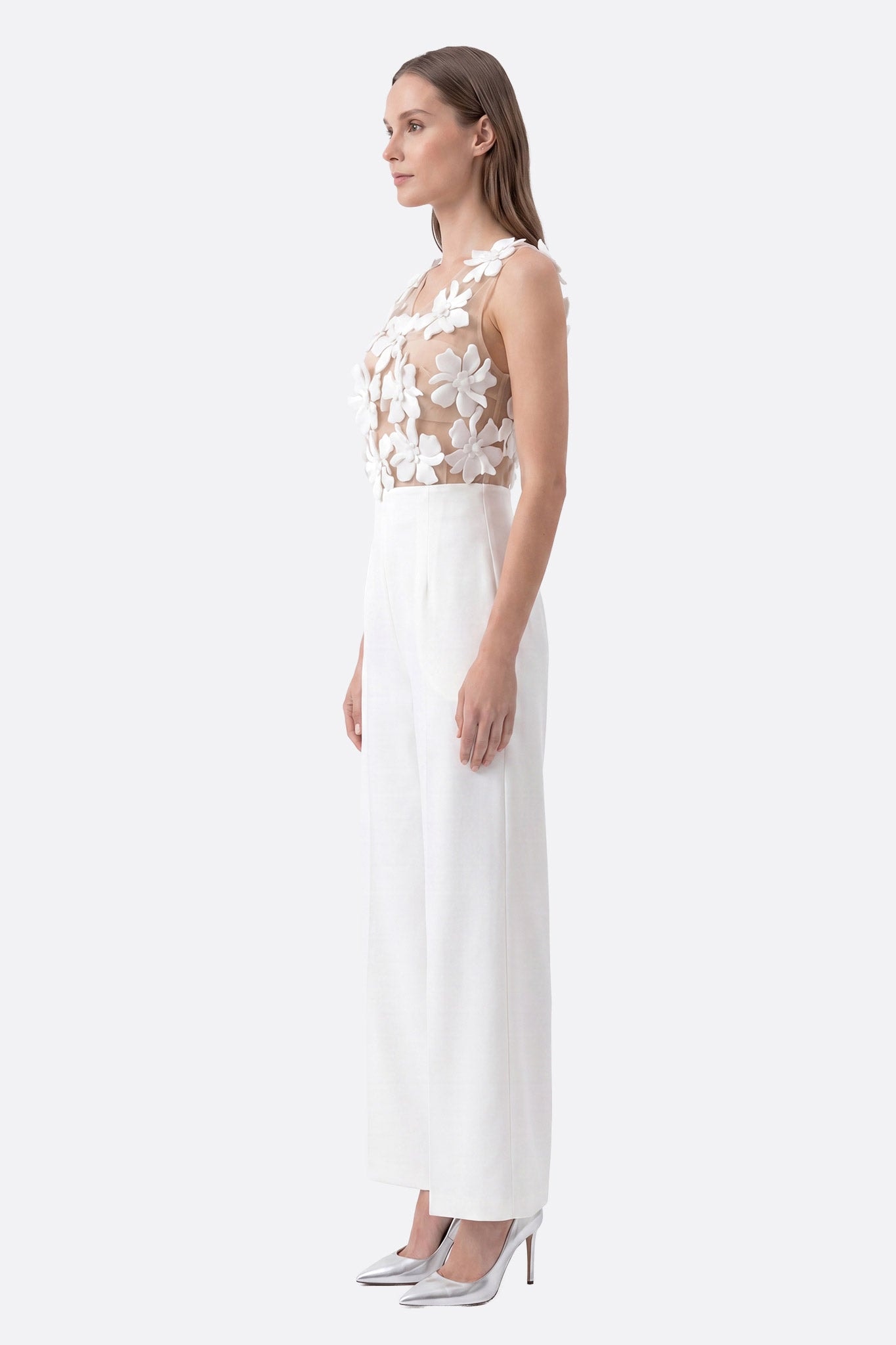 Mannequin de profil portant une combinaison blanche coupe large avec un bustier à fleurs 3D transparent