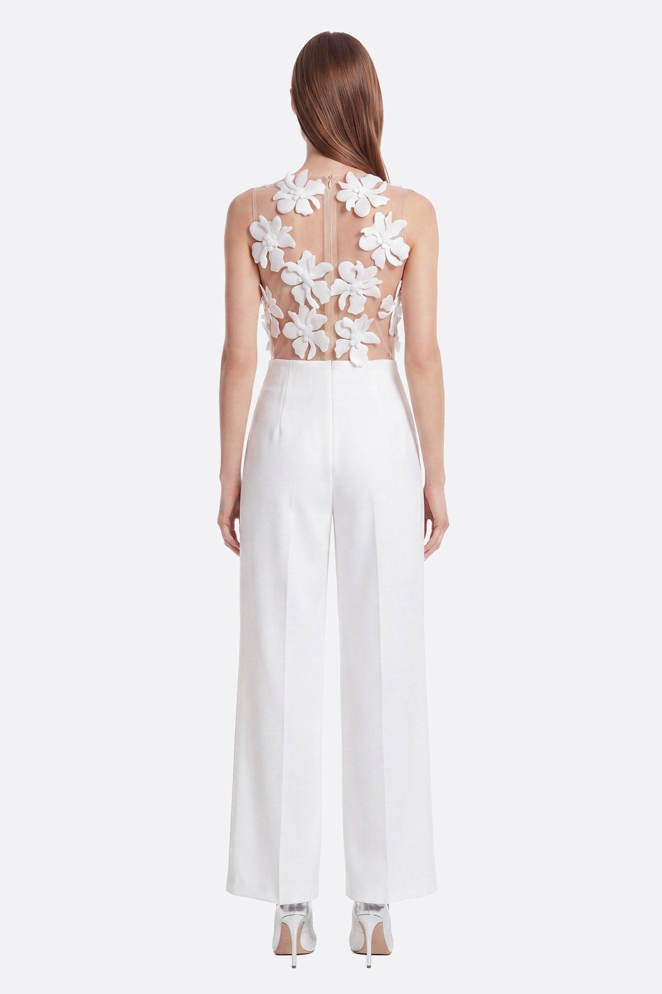 Mannequin de dos portant une combinaison blanche coupe large avec un haut transparent à fleurs 3D