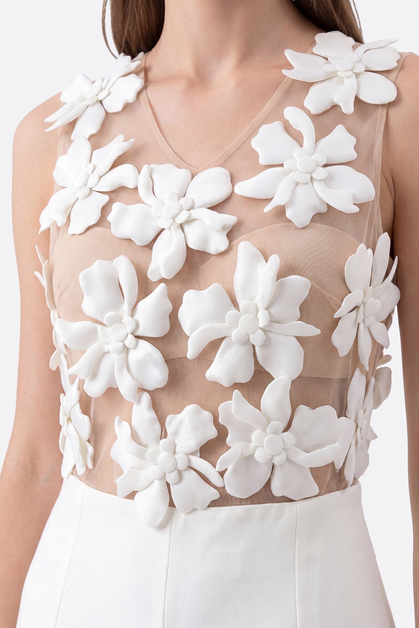 Zoom face sur le haut d'une combinaison blanche à fleurs 3D portée, col V en tulle transparent