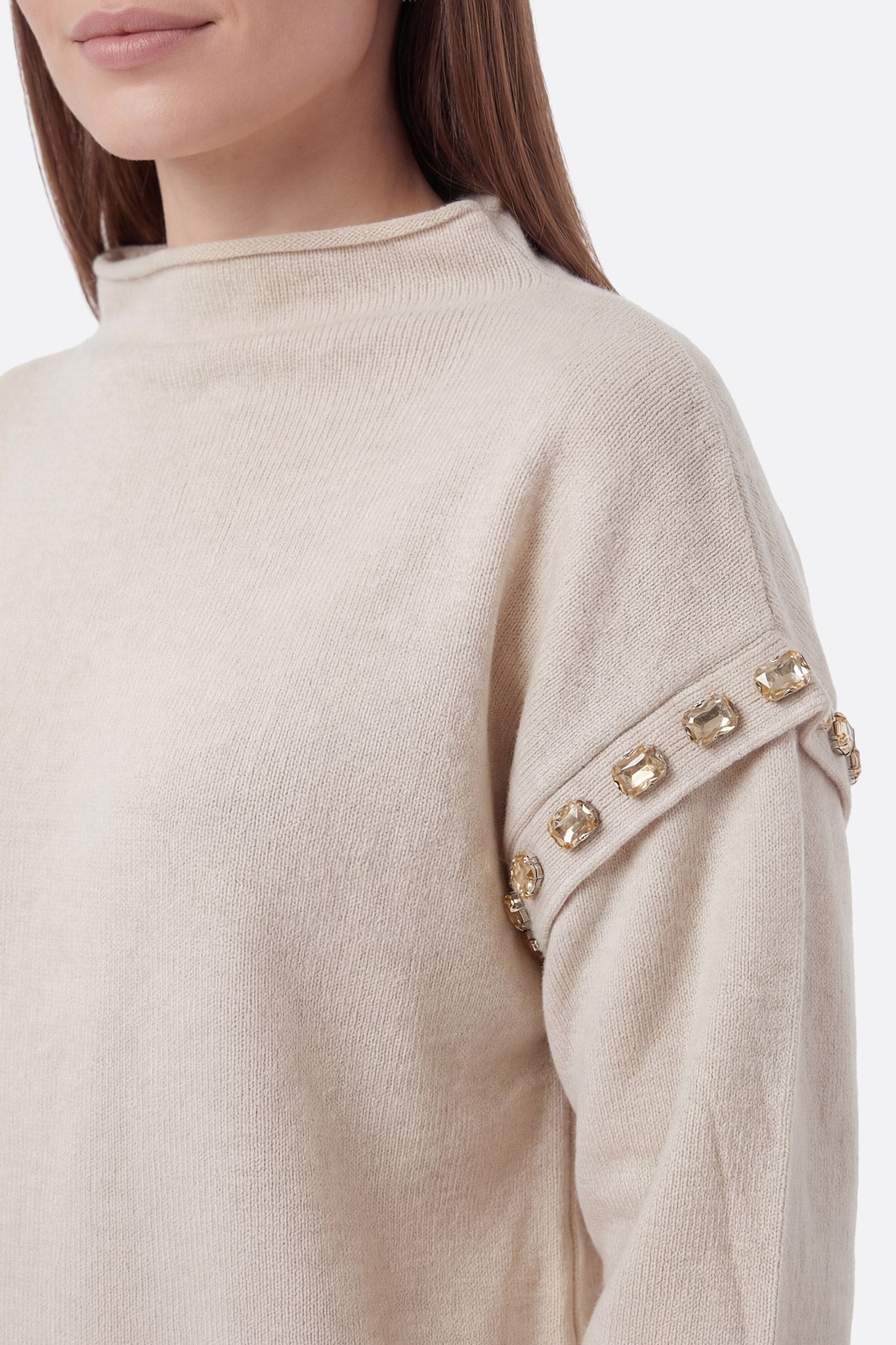 Zoom sur la jupe longue écru en maille, détails délicats soulignant l'élégance de cet ensemble chic pour occasions spéciales.
