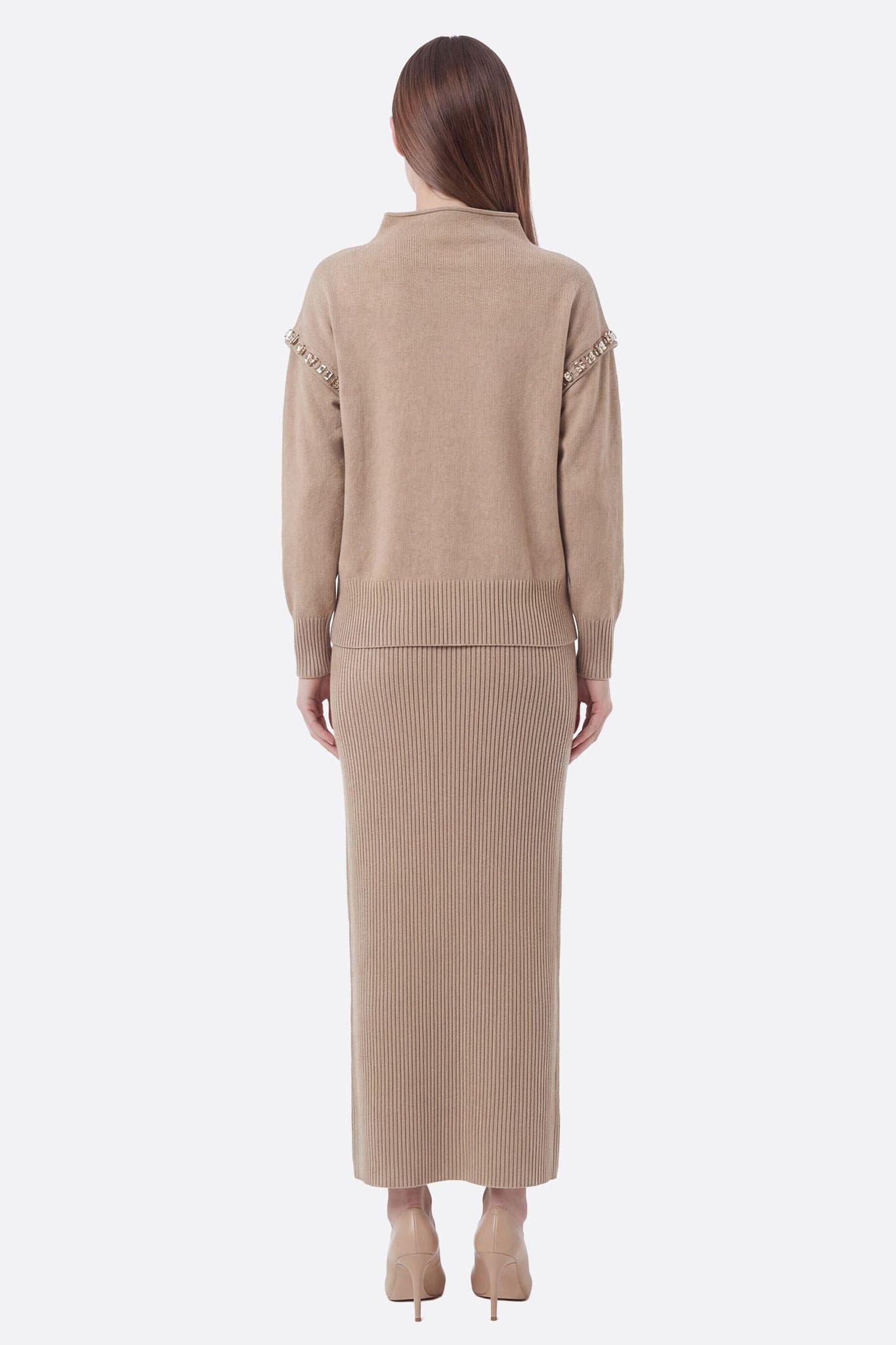 Detail of the beige knit sweater and long skirt, highlighting textures and elegant style for a chic look.