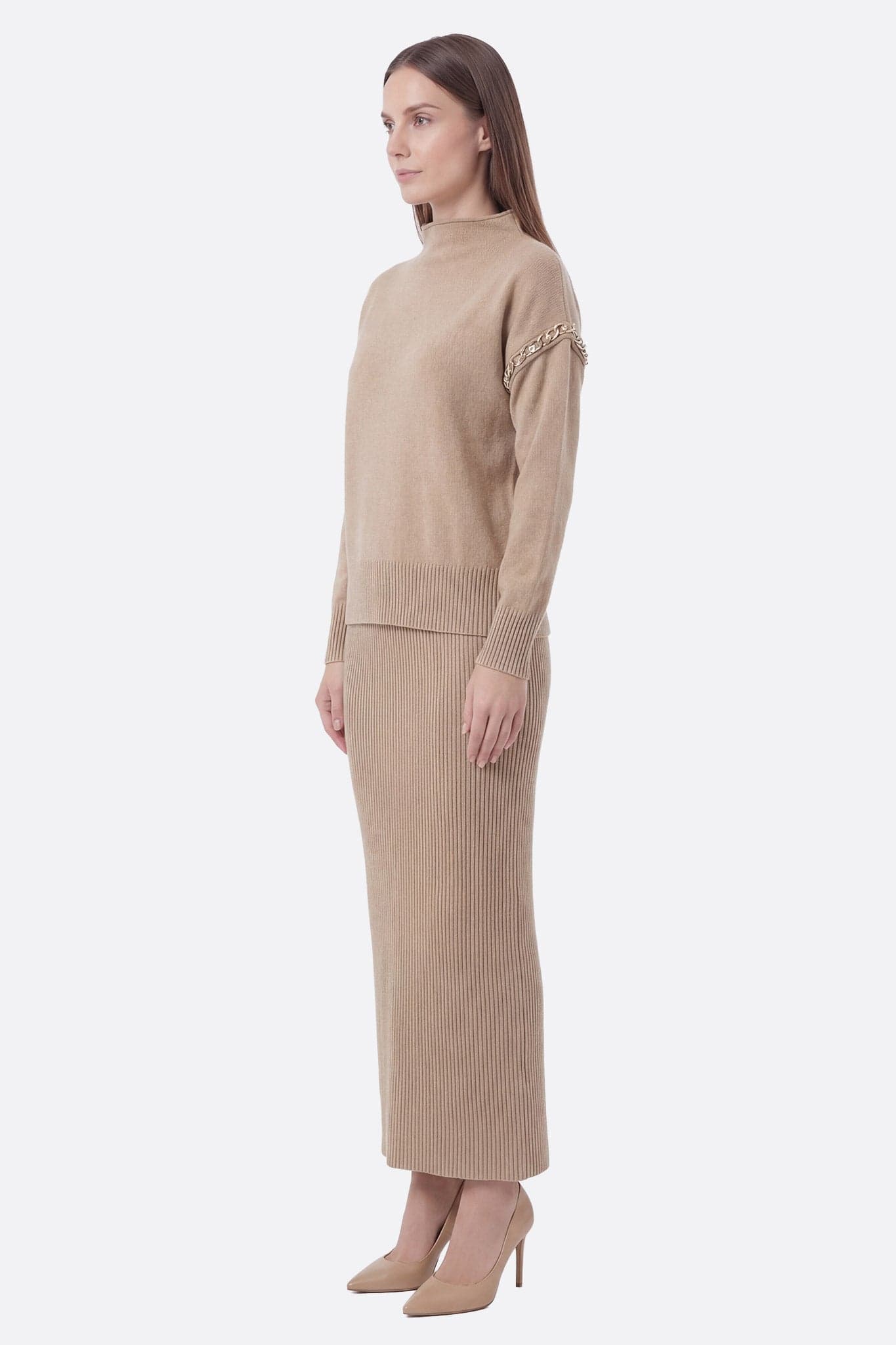 Detail of the set with beige long knit skirt and soft sweater, highlighting delicate finishes and refined style.