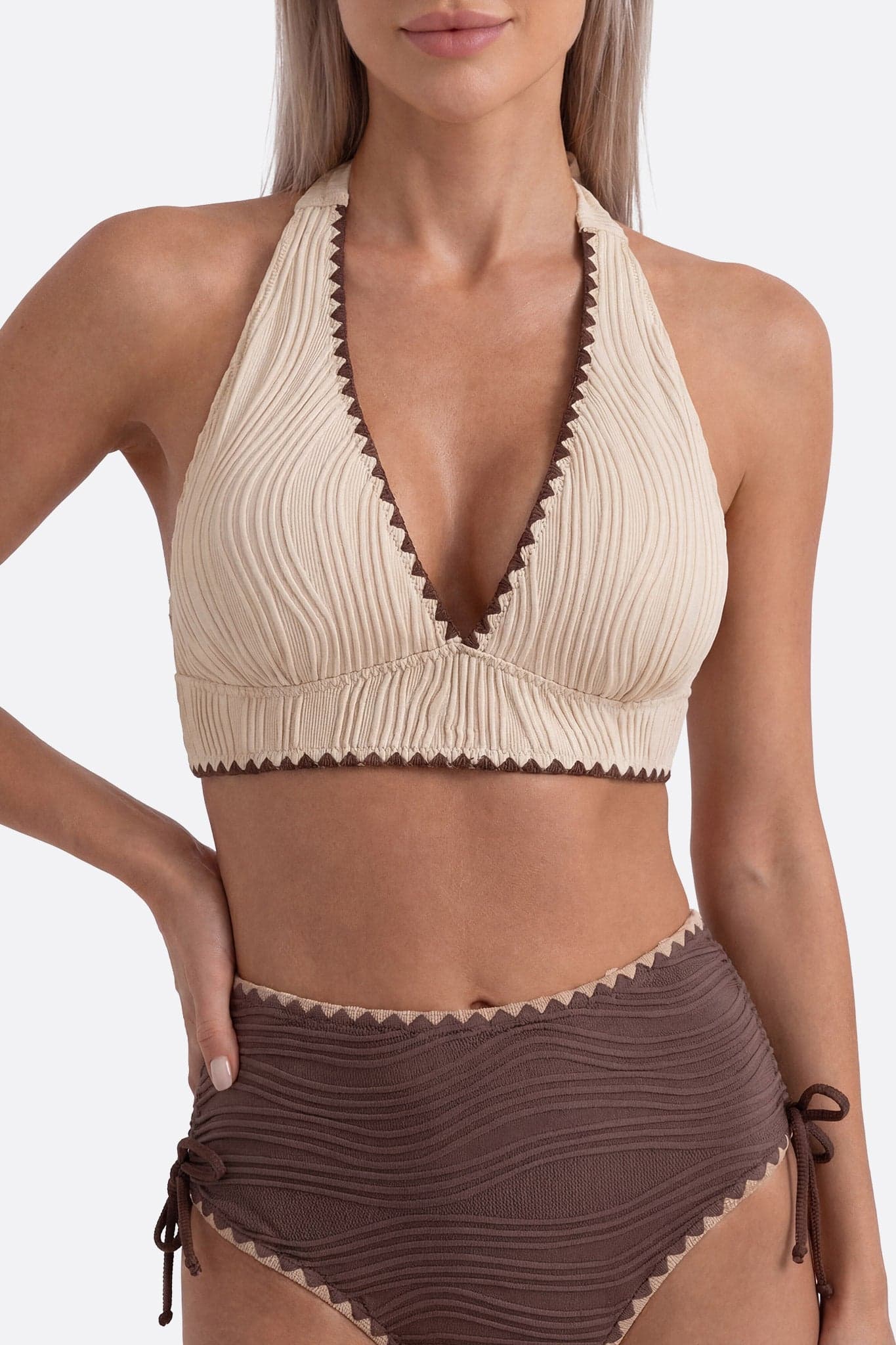 Fokus auf die hohe Taille des beigen und braunen texturierten Bikinis, ideal für stilvolle Ferien am Meer.