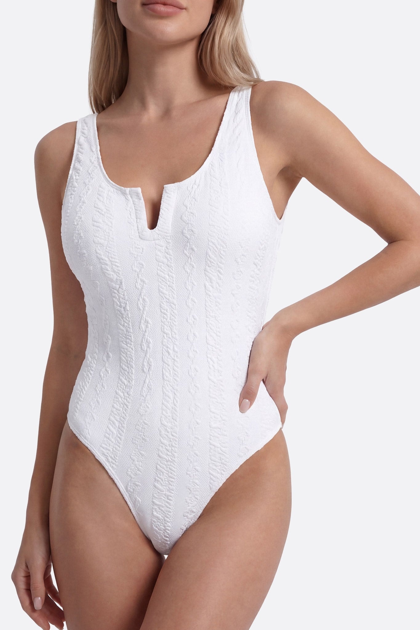 Primo piano del costume intero bianco con scollo a U, che ne esalta la texture delicata e l'eleganza