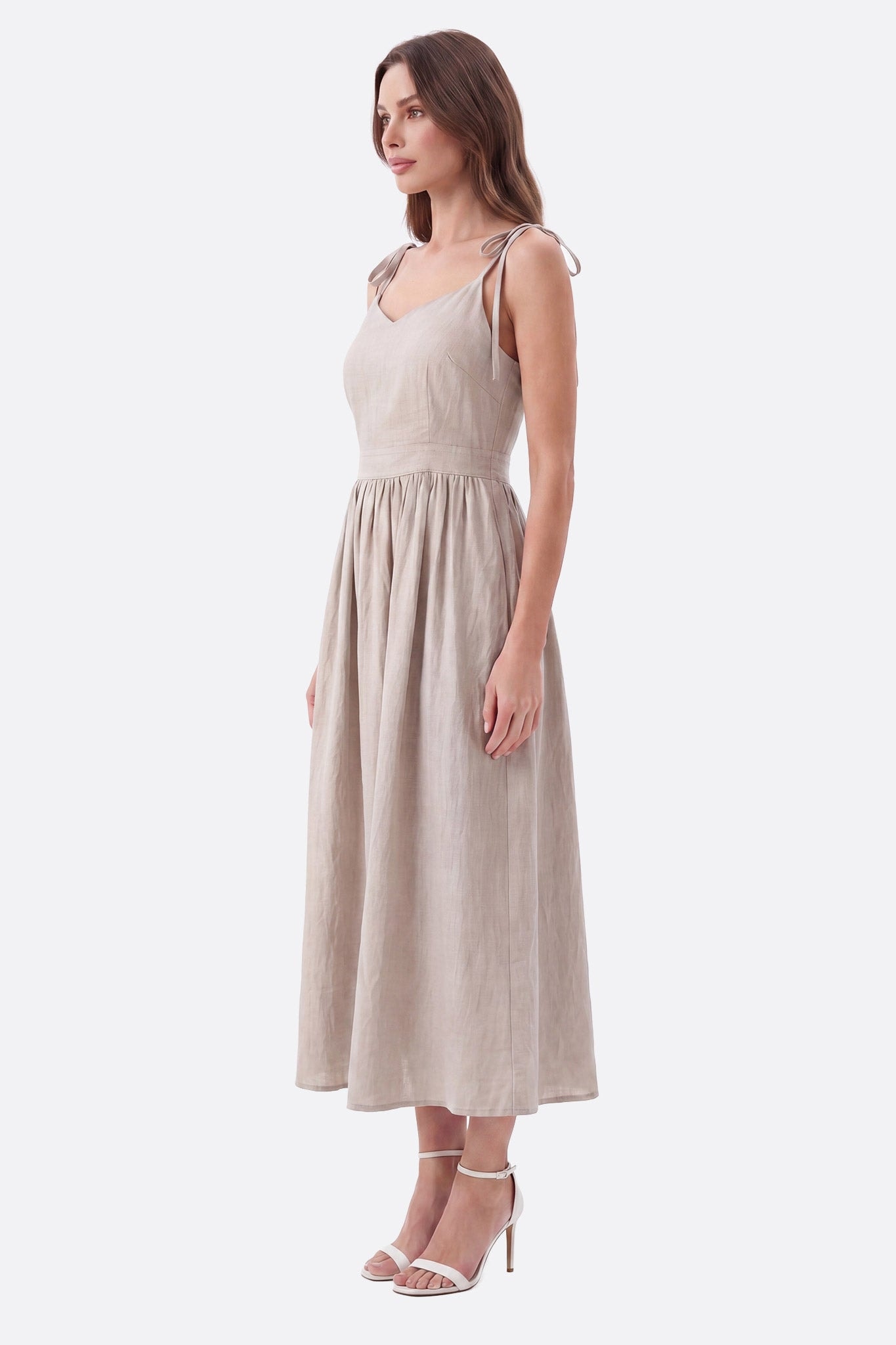 Mannequin de profil portant une robe midi beige à bretelles nouées et dos ouvert