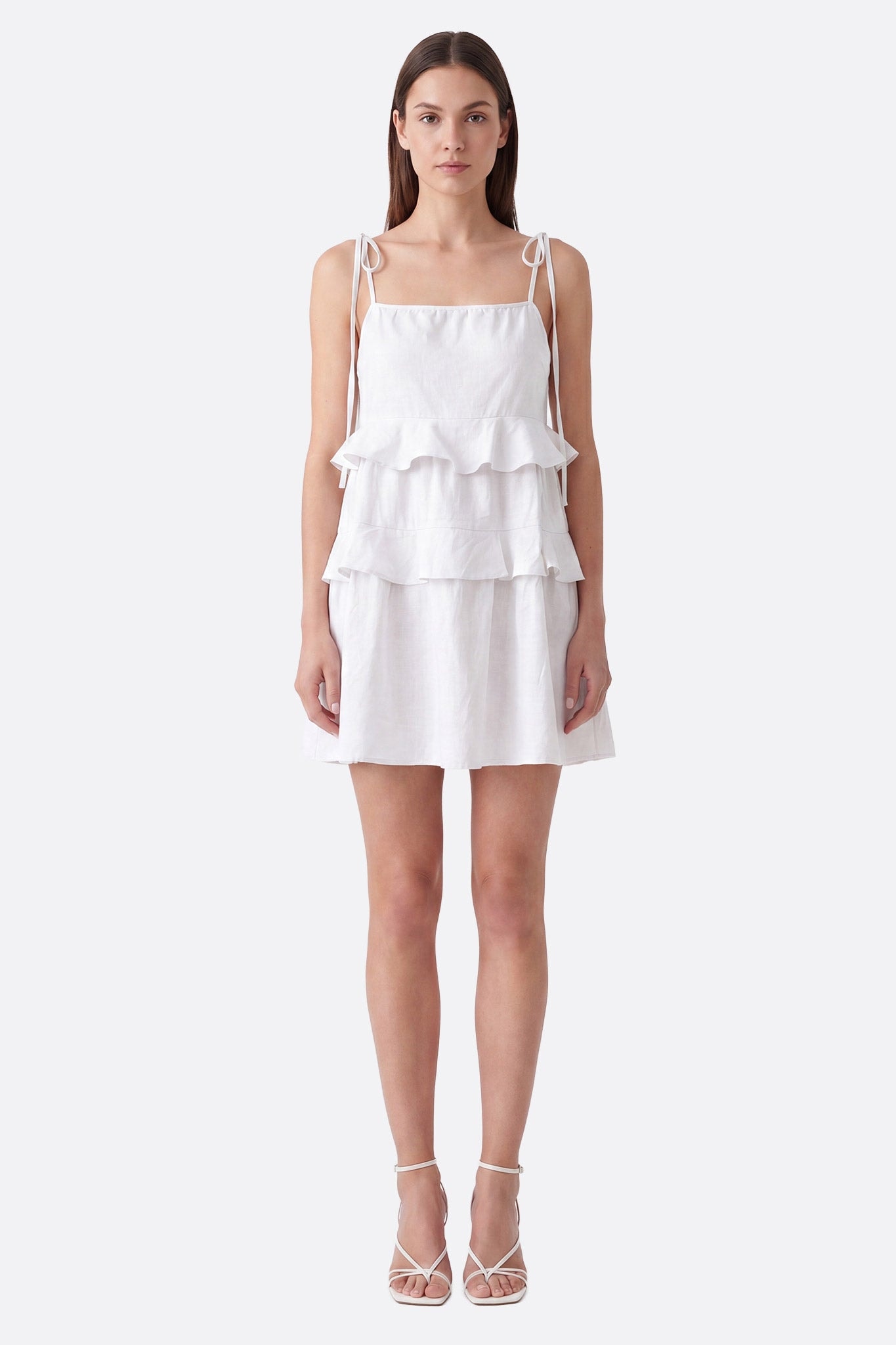 Vestido corto blanco con volantes y tirantes anudados llevado de frente sobre maniquí