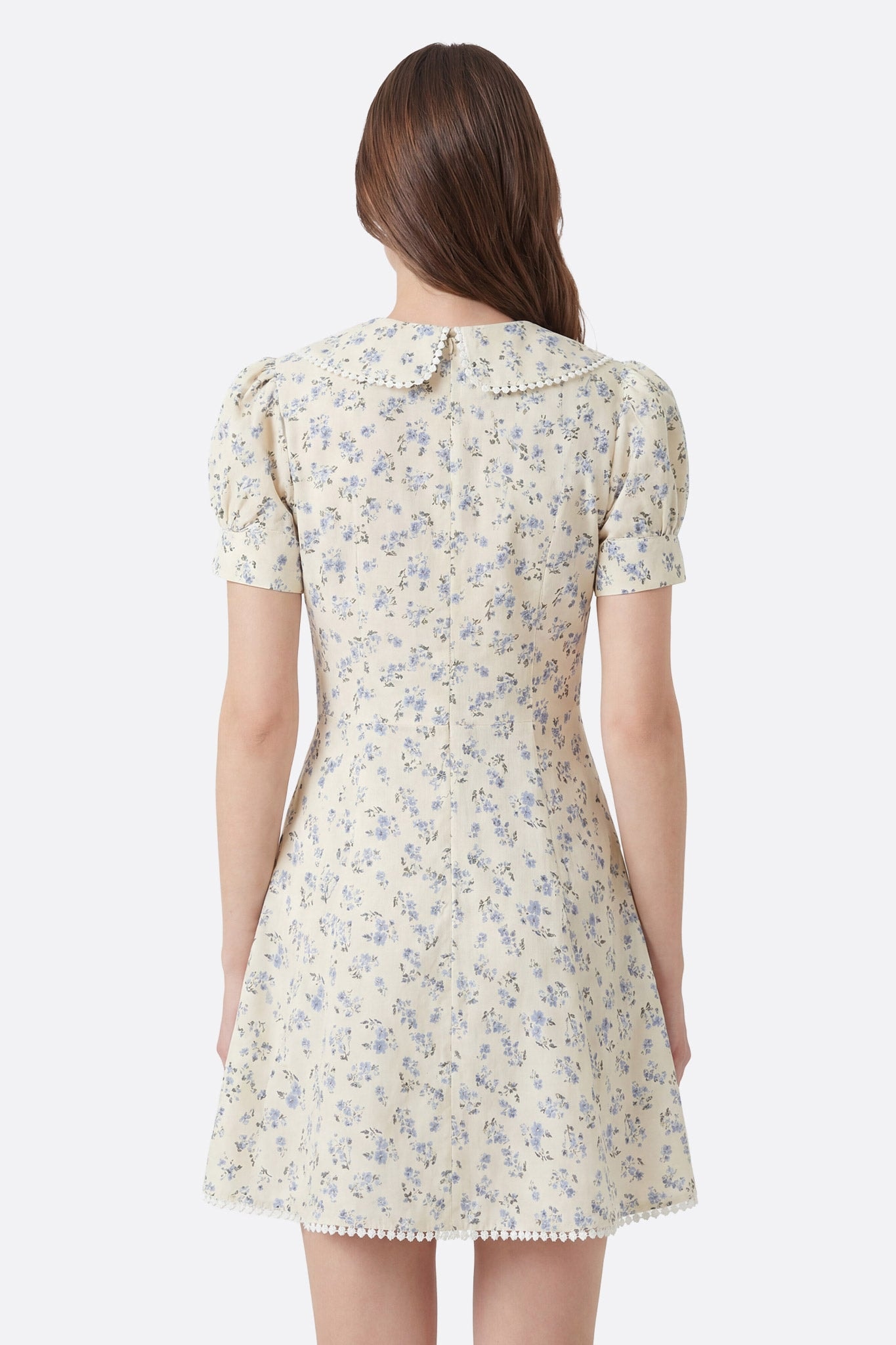 Vestido corto floral de algodón con cuello claudine visto de espaldas, detalle del cuello y del dobladillo