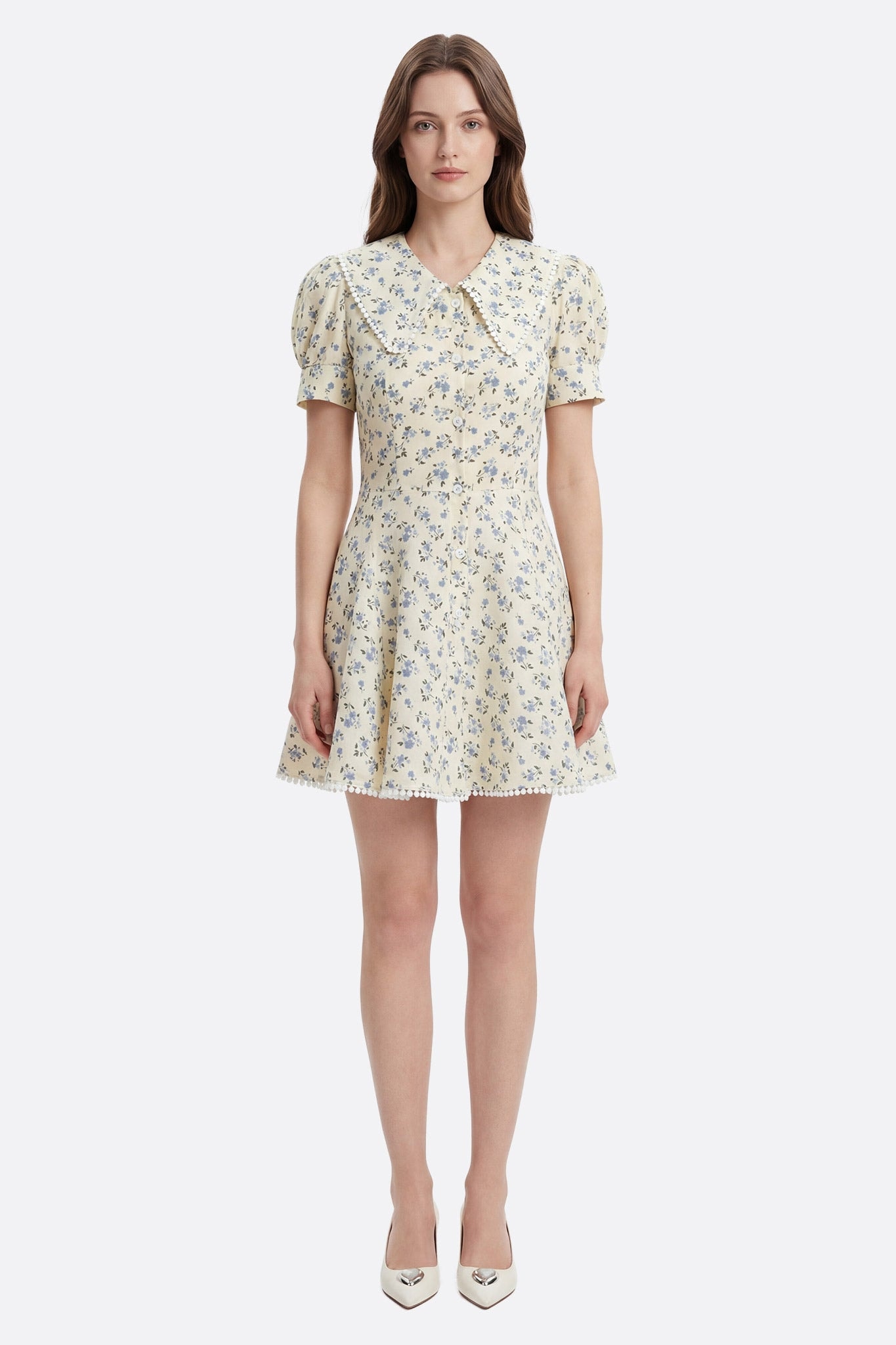 Modelo de frente con vestido corto floral de algodón amarillo pálido, cuello claudine y borde de pompones