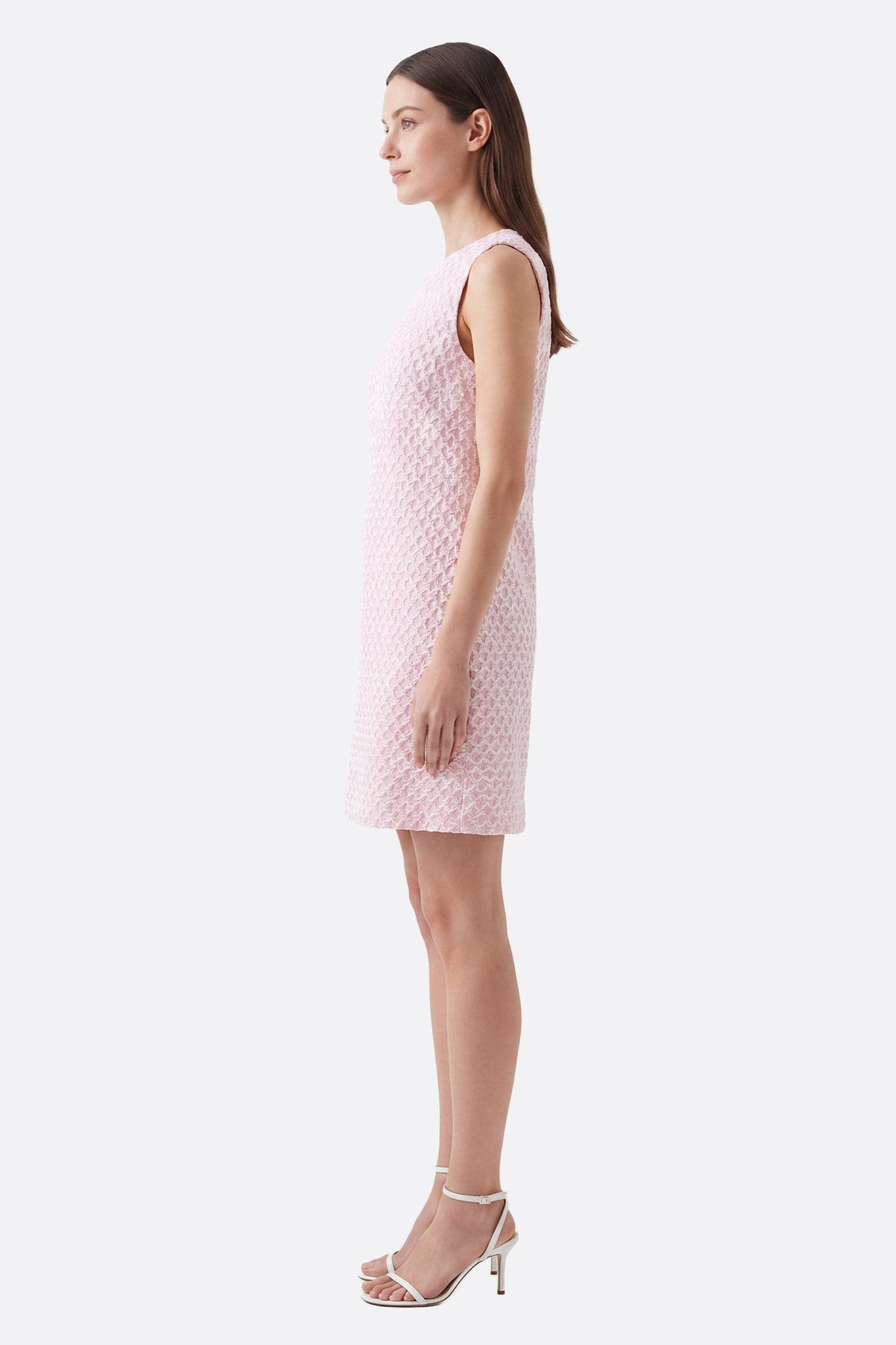 Abito corto rosa a texture goffrata indossato di profilo da una modella, dettaglio del tessuto