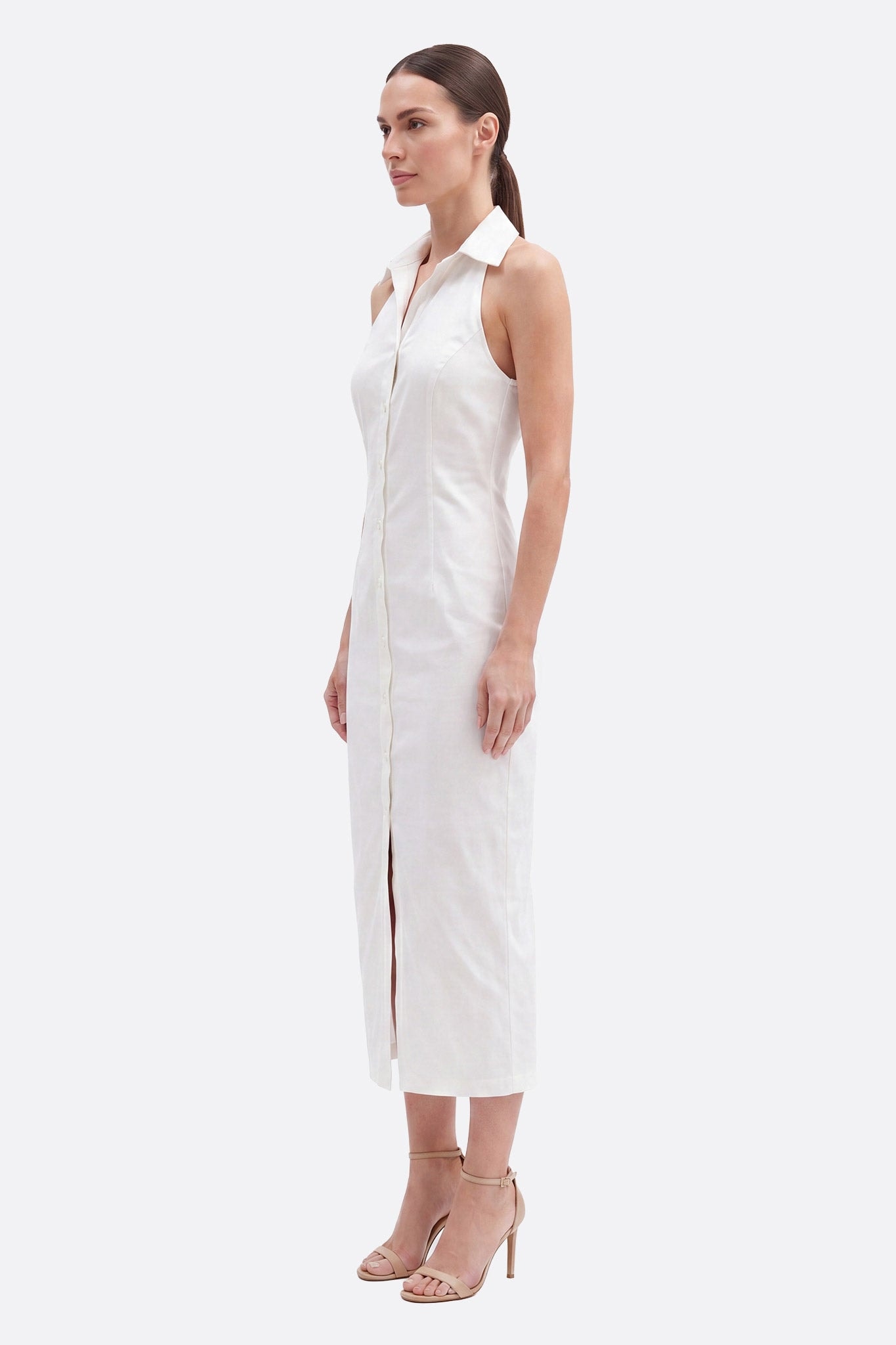 Modella di profilo in abito midi bianco con colletto camicia, abbottonato sul davanti