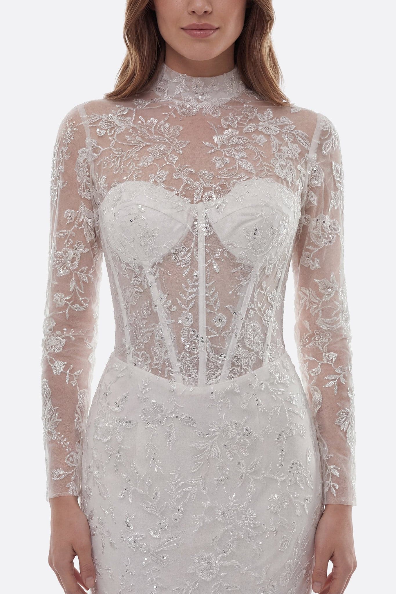 Abito da sposa sirena in pizzo avorio, maniche lunghe, primo piano sullo strascico ricamato che aggiunge un tocco romantico.