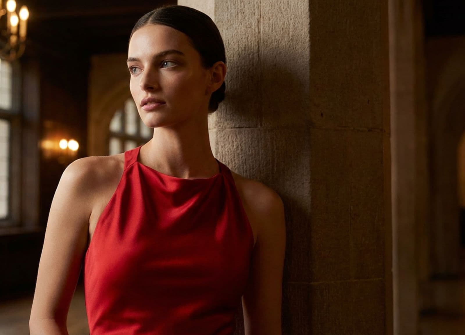 Mannequin en robe de soirée rouge satinée, décolleté halter, posant dans un intérieur élégant
