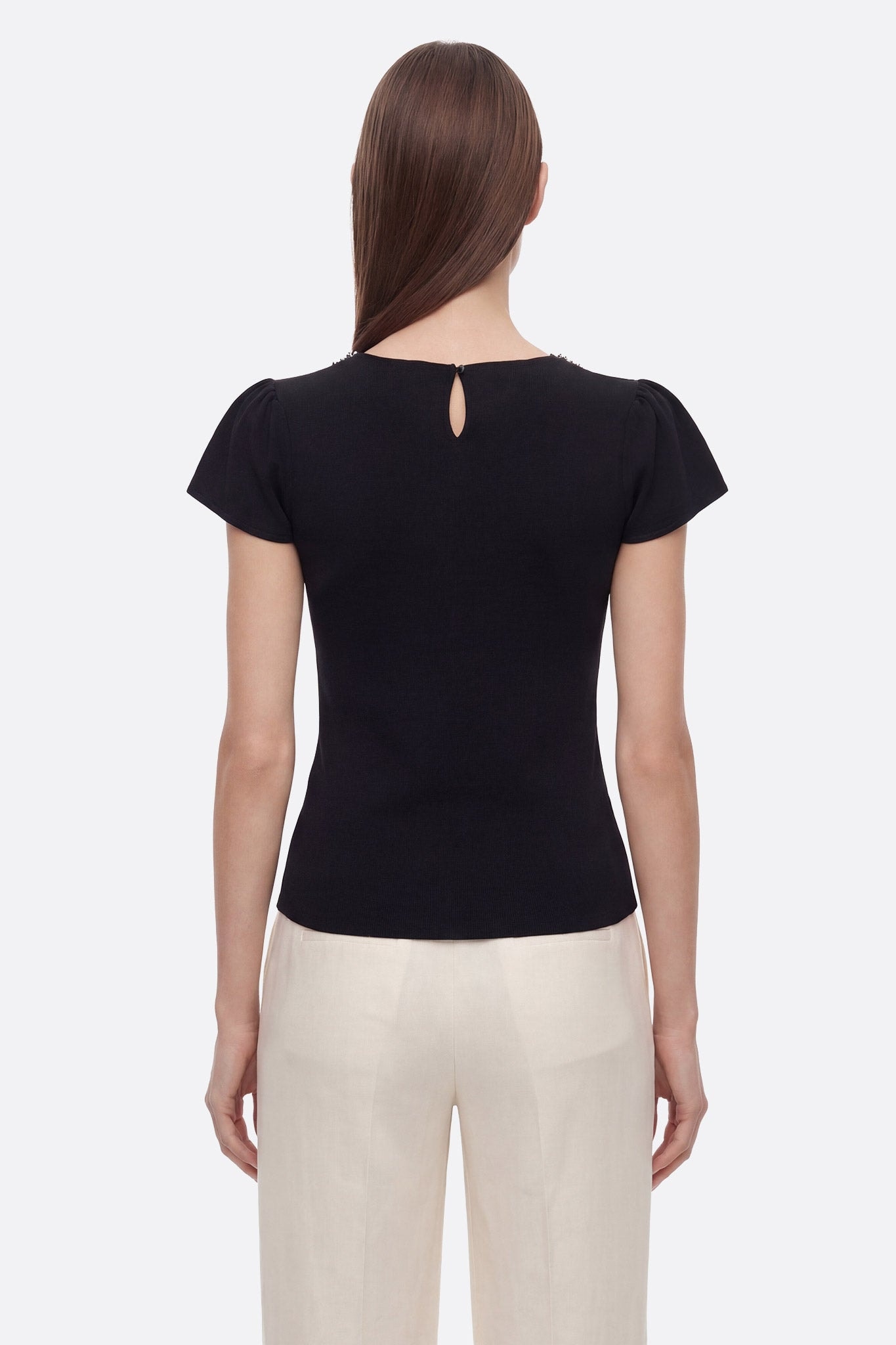 Elegantes Detail des Schmuckkragens am schwarzen Stretch-Strick-T-Shirt, das jedem Outfit eine raffinierte Note verleiht.