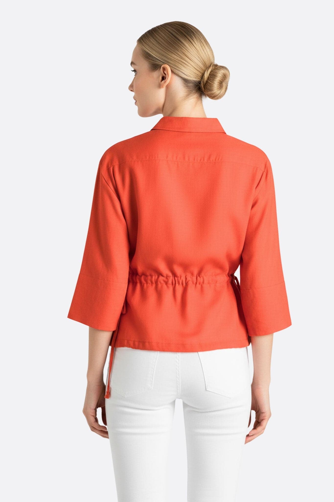 Vista alternativa della blusa in lino rosso corallo, che mette in risalto la texture ariosa e i lacci regolabili per un...