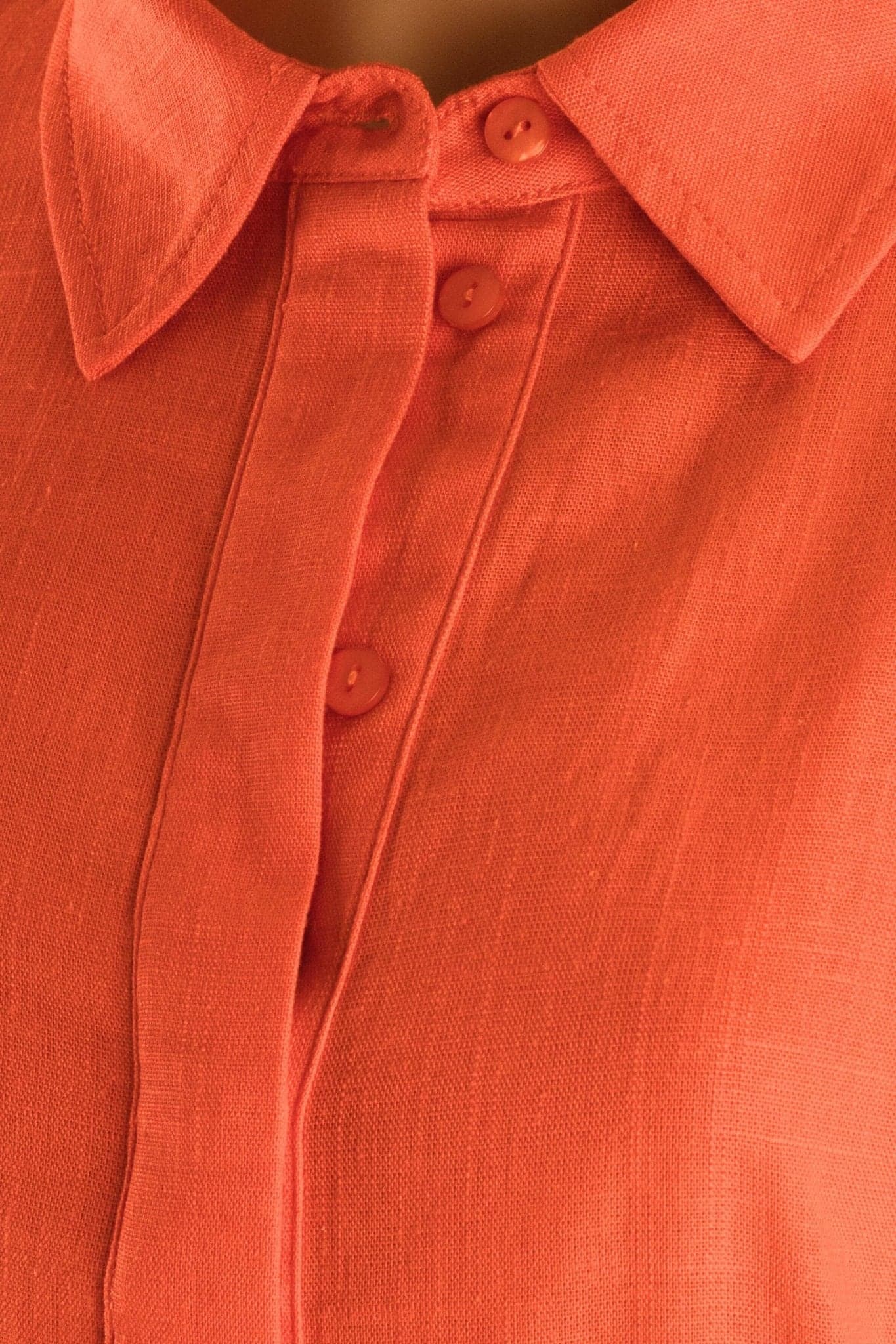 Dettaglio alternativo della blusa in lino rosso corallo, che ne sottolinea i lacci regolabili e il taglio fluido, perfetta per una...