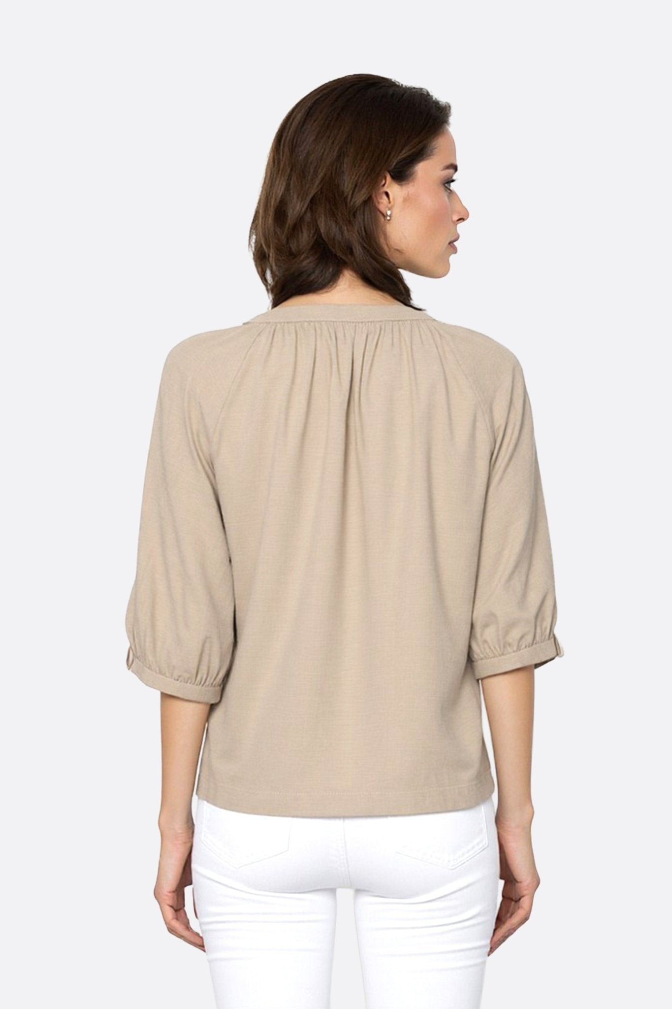 Detail of the back of the beige linen blouse, highlighting the delicacy of the buttons and the light drape of the sleeves...