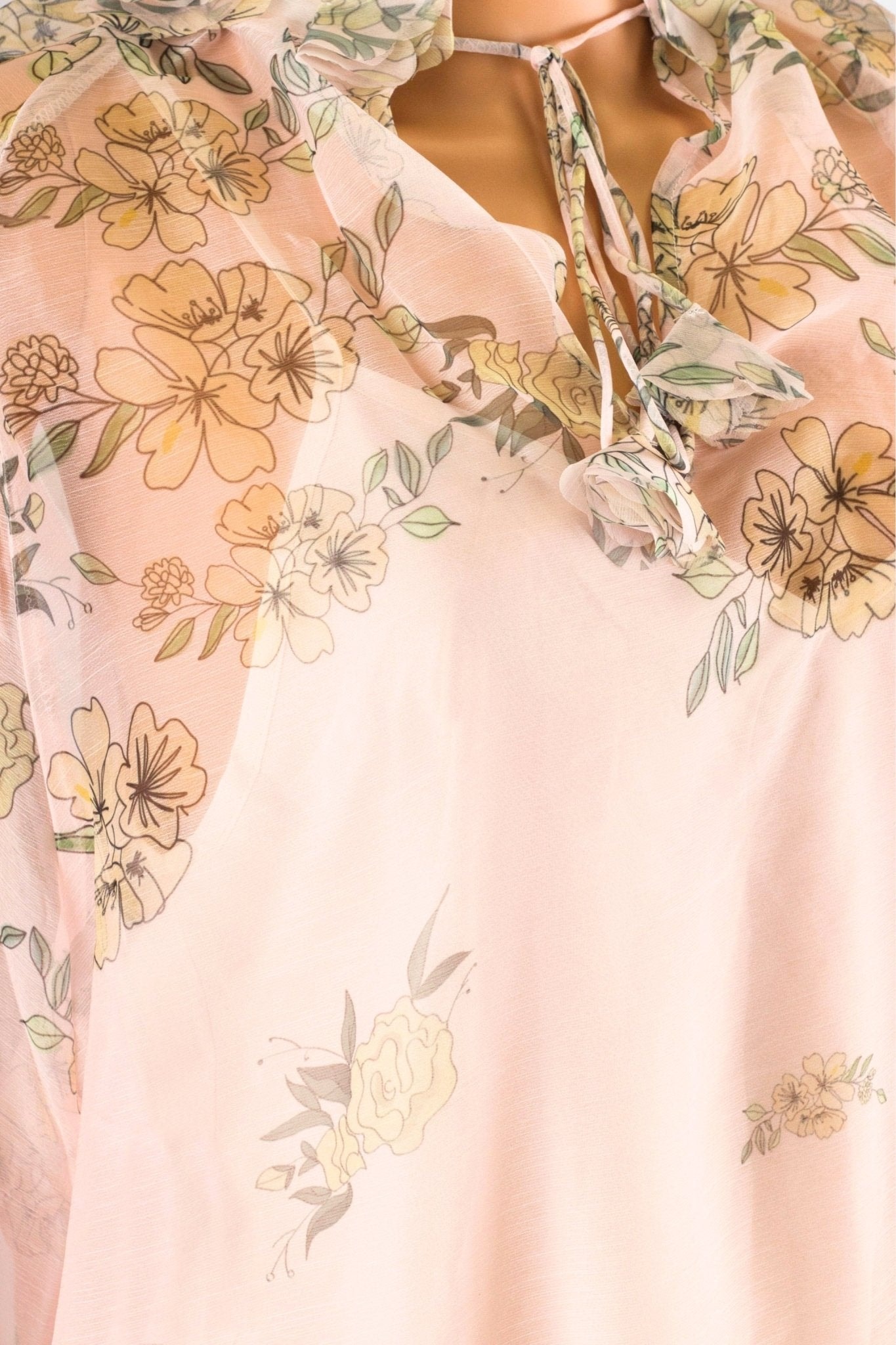 Detail of the back of a pastel pink voile blouse adorned with flowers, chic and airy, ideal for a spring evening.