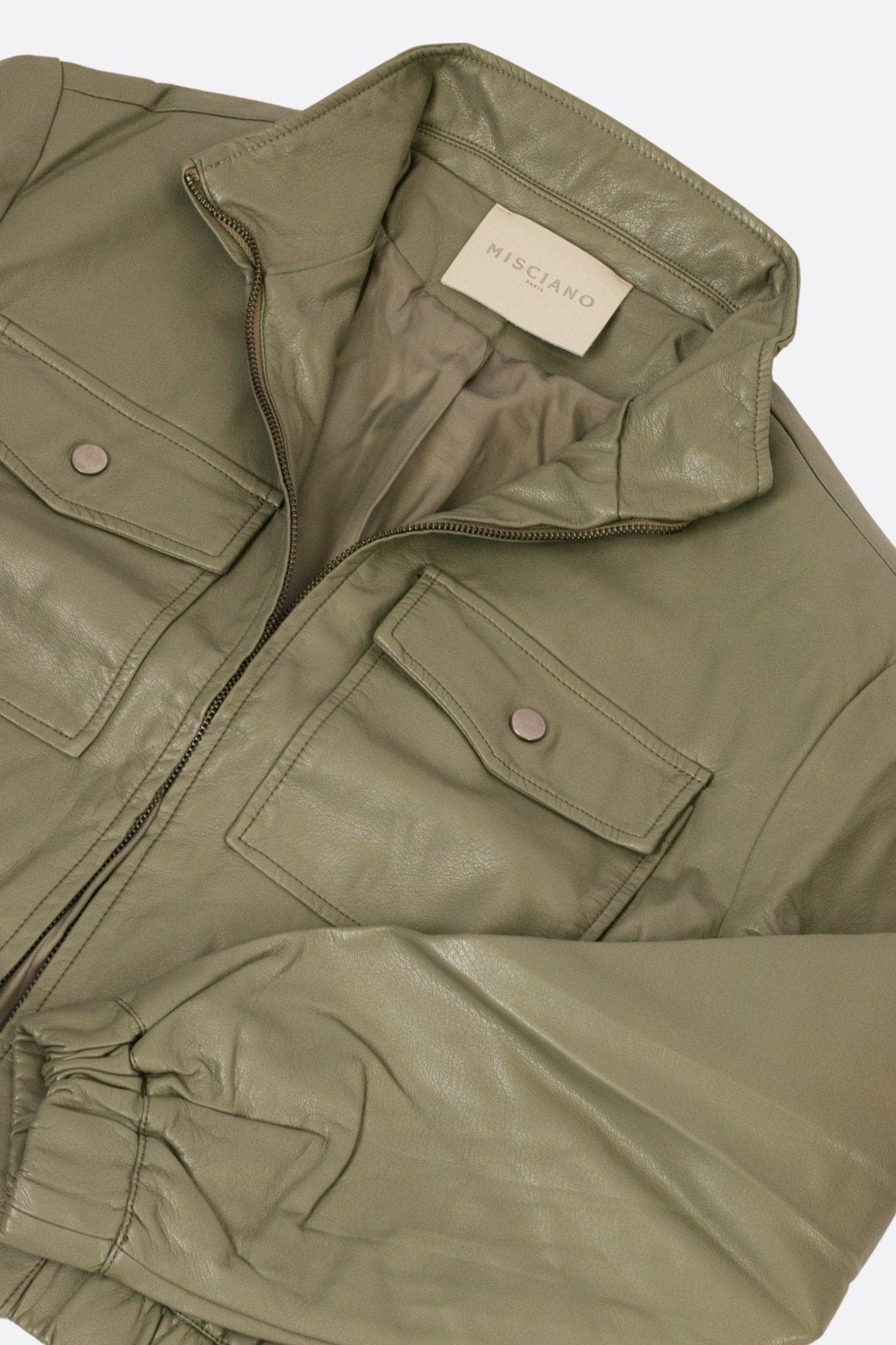 Detail of the khaki faux leather bomber, showing the rich texture and impeccable finish, perfect for an urban look...