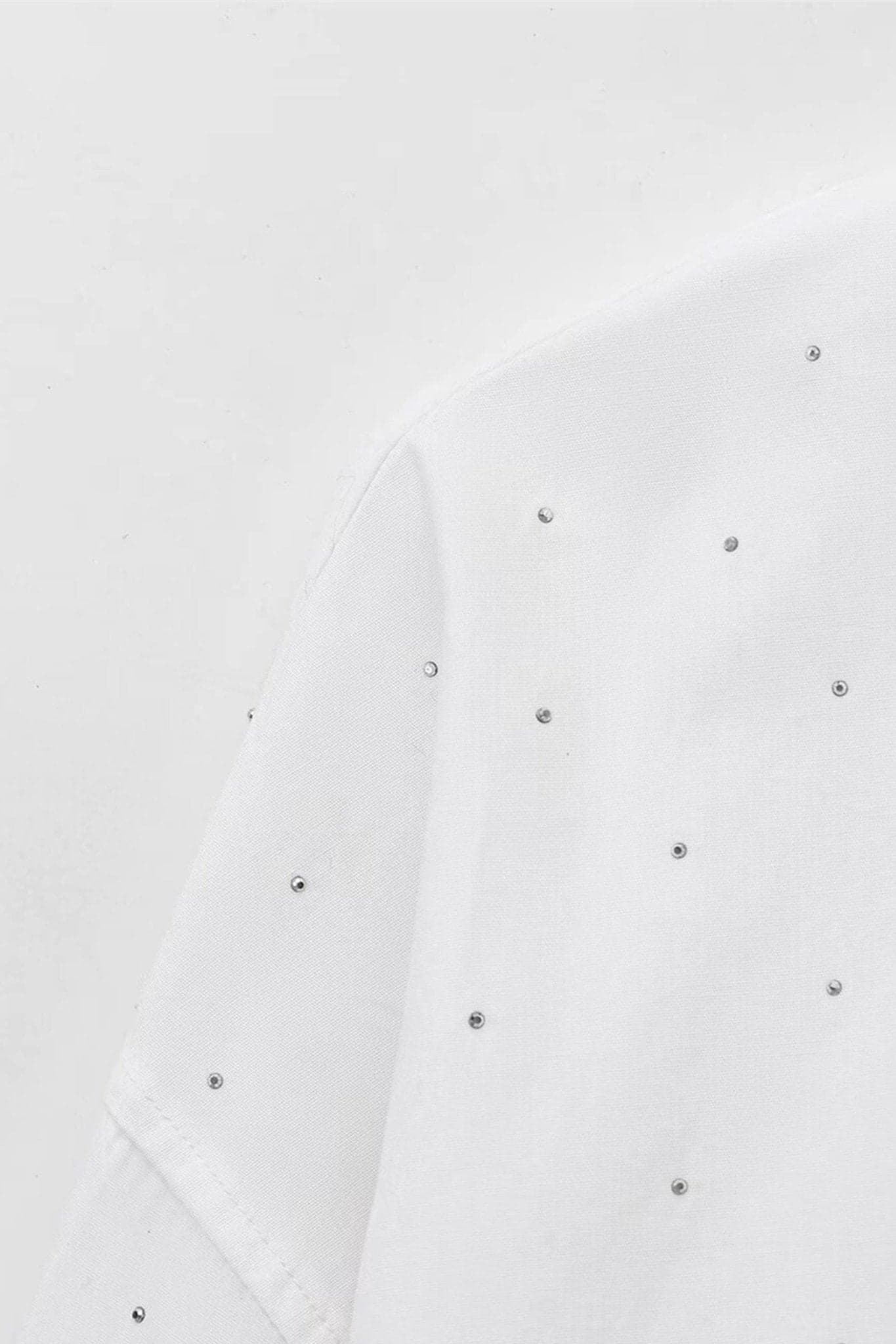Nahaufnahme des Oversize-weißen Hemds mit Strass, ein elegantes Stück für raffinierte Abendoutfits