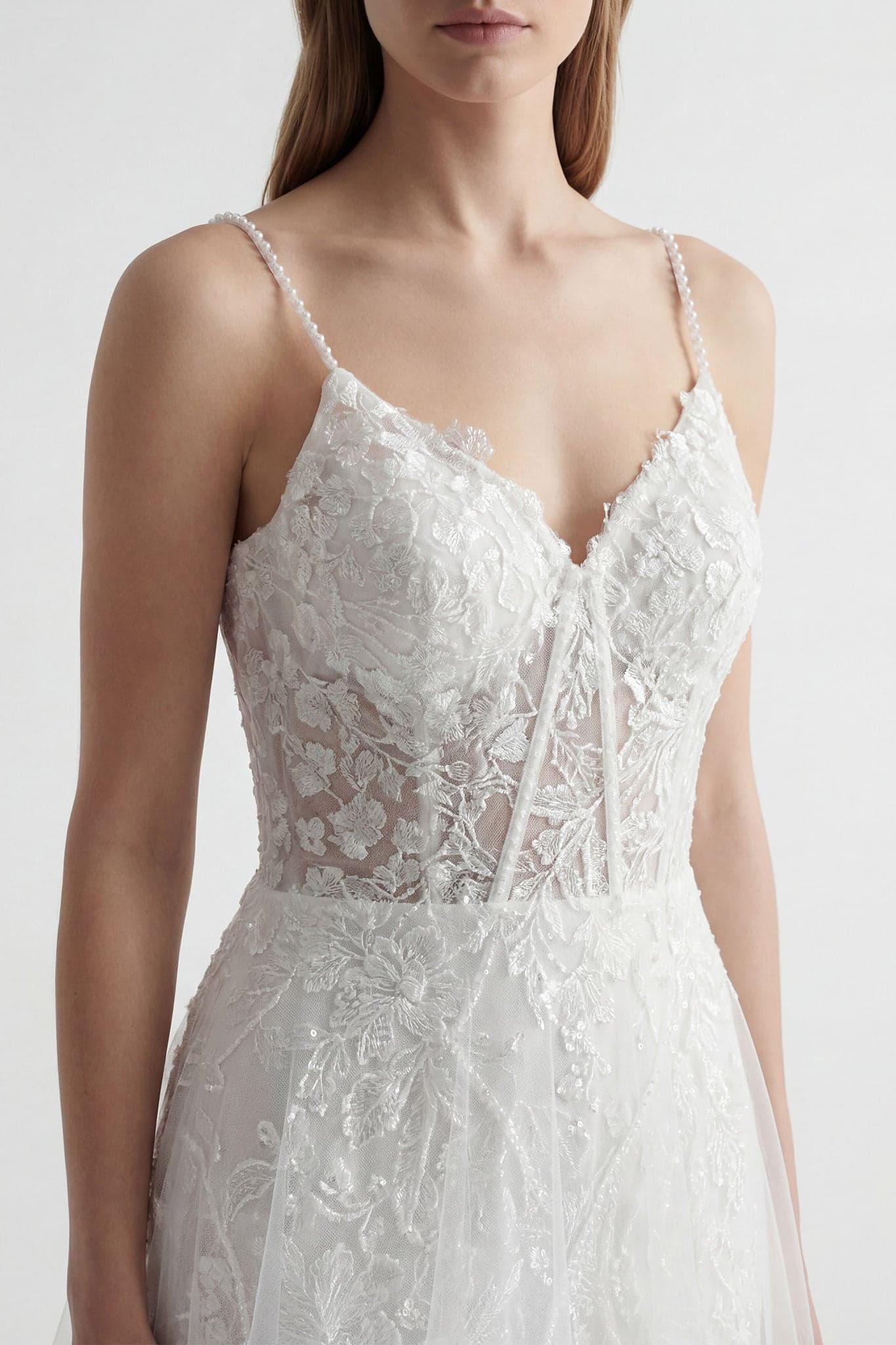 Marla-Kleid aus weißem Tüll und Spitze, das die Fließfähigkeit der Materialien und die eleganten dünnen Träger betont.