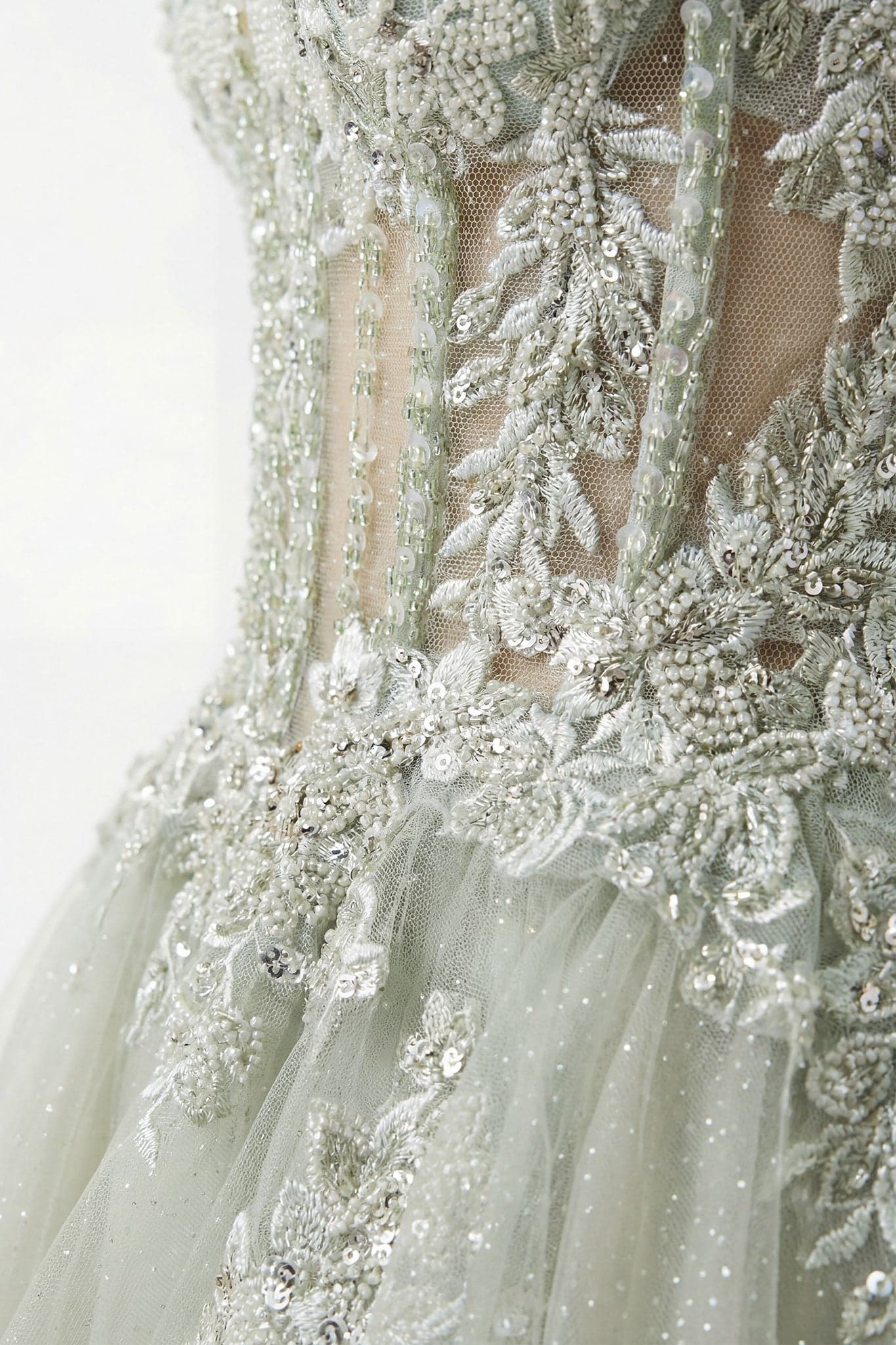Détail sur la texture en tulle de la jupe fendue de la robe de soirée vert sauge, ajoutant une élégance aérienne à votre...