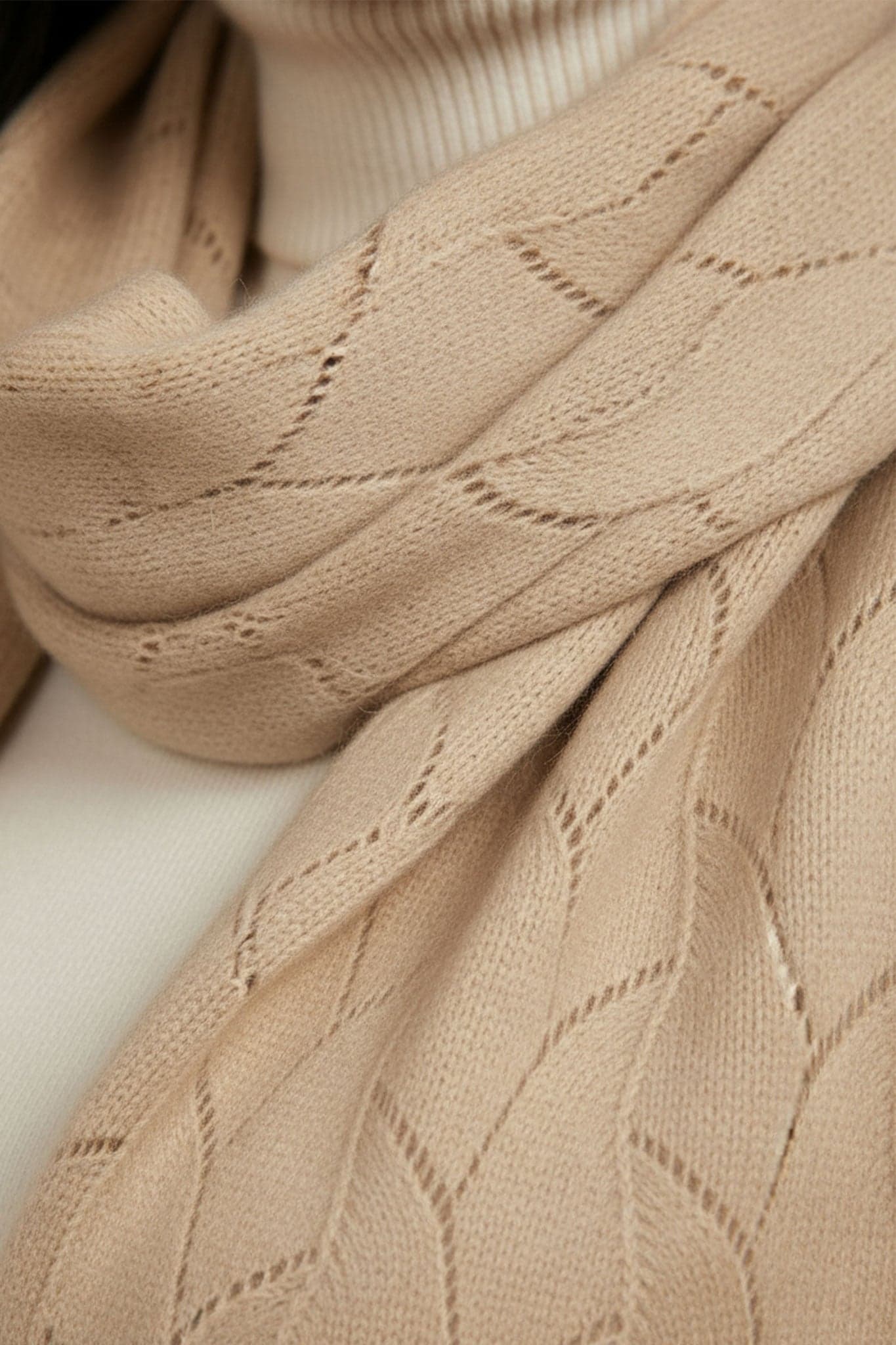 Écharpe beige en cachemire à maille ajourée, vue 3/4 mettant en lumière sa texture douce, parfaite pour un look élégant...