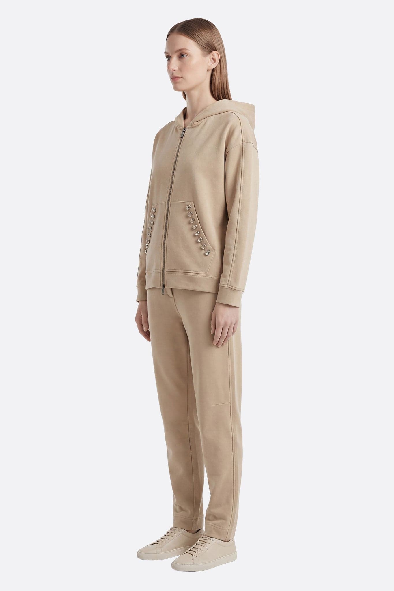 Détail d'un ensemble de survêtement beige embellie de cristaux, idéal pour une soirée chic ou un look quotidien raffiné.