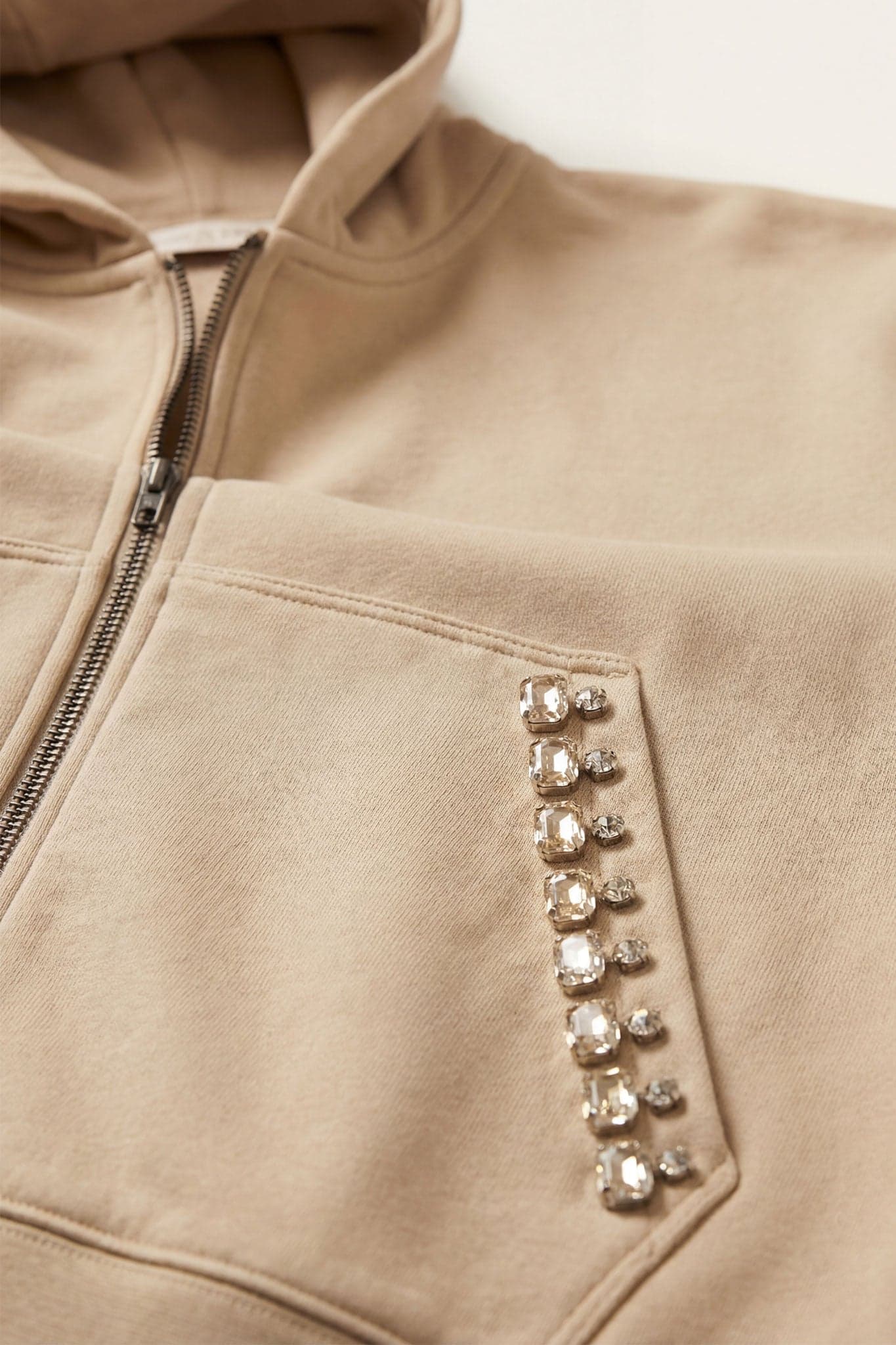Zoom détail à plat sur le jogging femme beige, poche latérale ornée de cristaux facettés