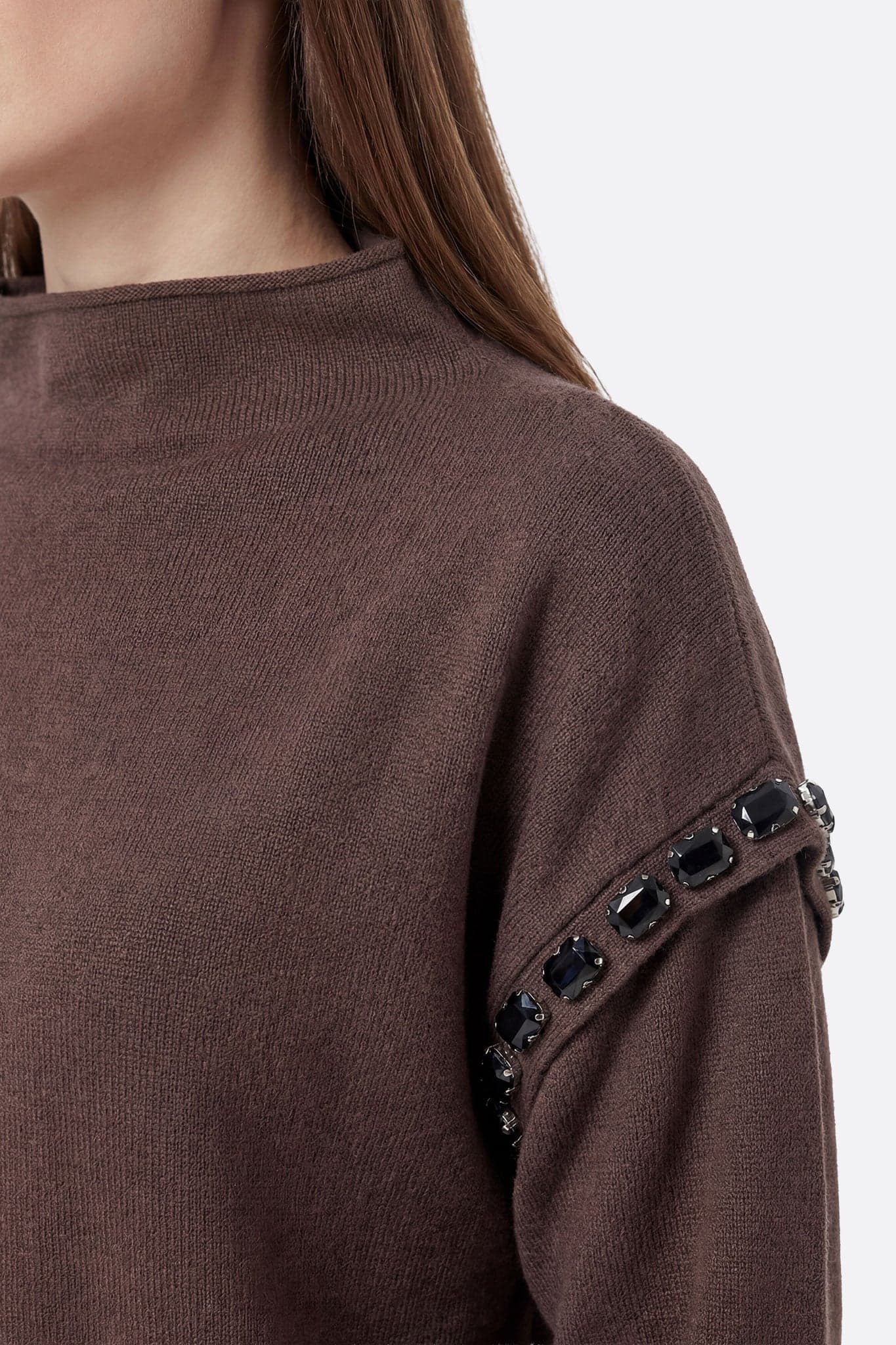 Détail raffiné de l'ensemble jupe longue et pull marron en maille, parfait pour un look chic lors d'une soirée décontractée.