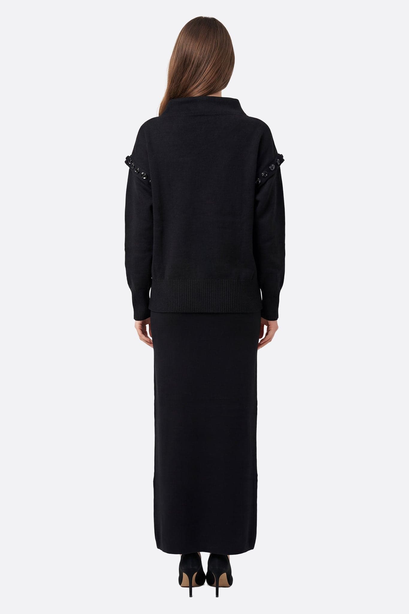 Elegant detail of the black knit sweater and the long skirt, a perfect ensemble for a refined everyday look.