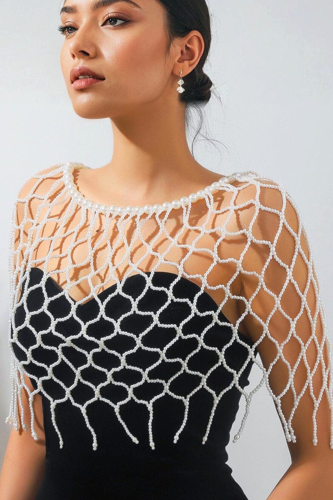 Artistic detail of the ivory pearl stole, a modern accessory for a chic silhouette at nighttime events.