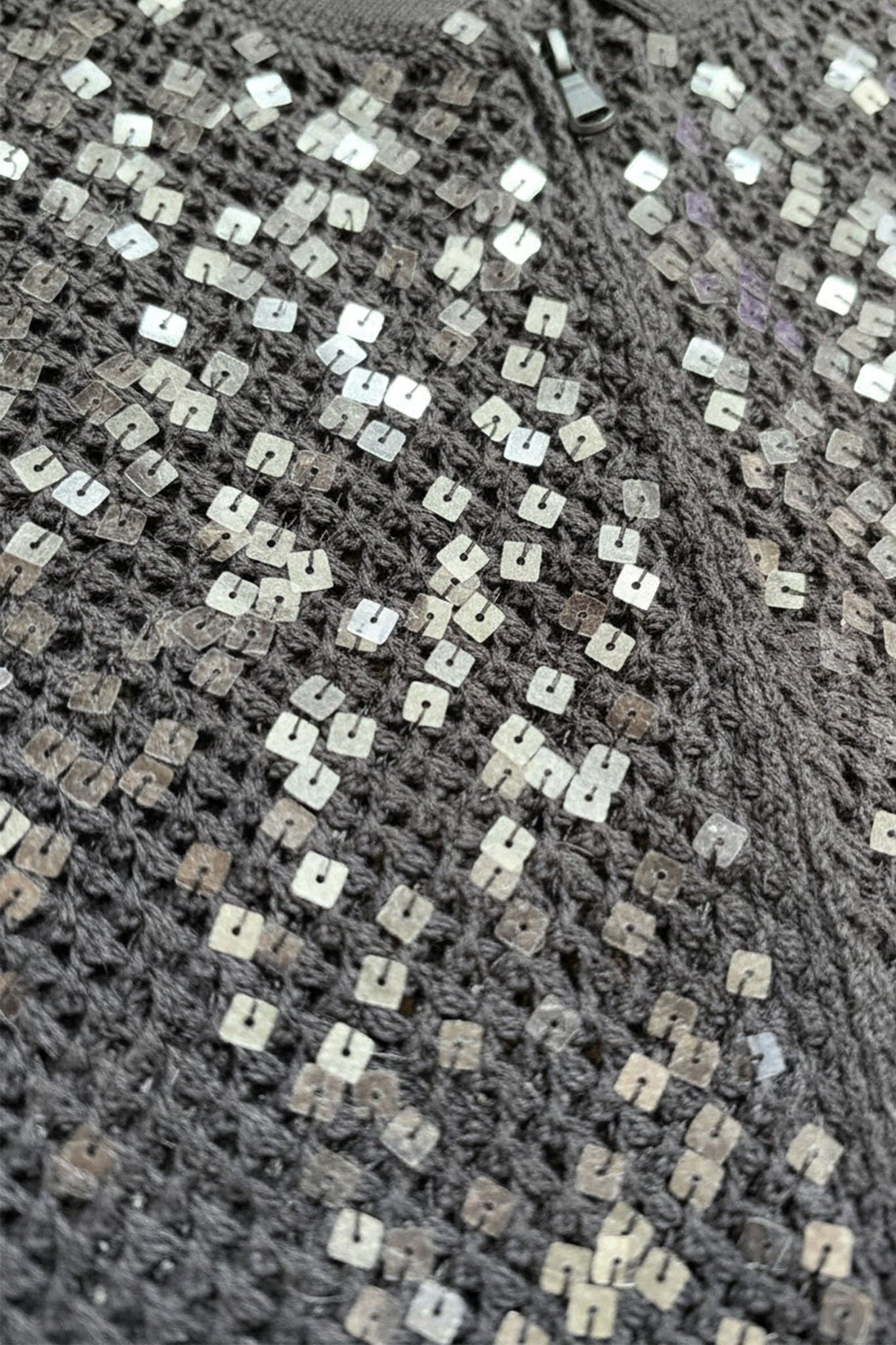 Vista cercana del chaleco gris en lino y algodón, destacando las lentejuelas brillantes para un toque de elegancia...