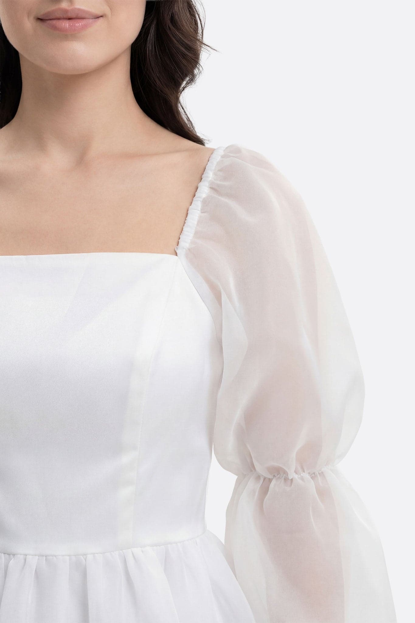 Front-facing close-up on the square neckline and sheer puffed sleeve of the white Lauren short dress