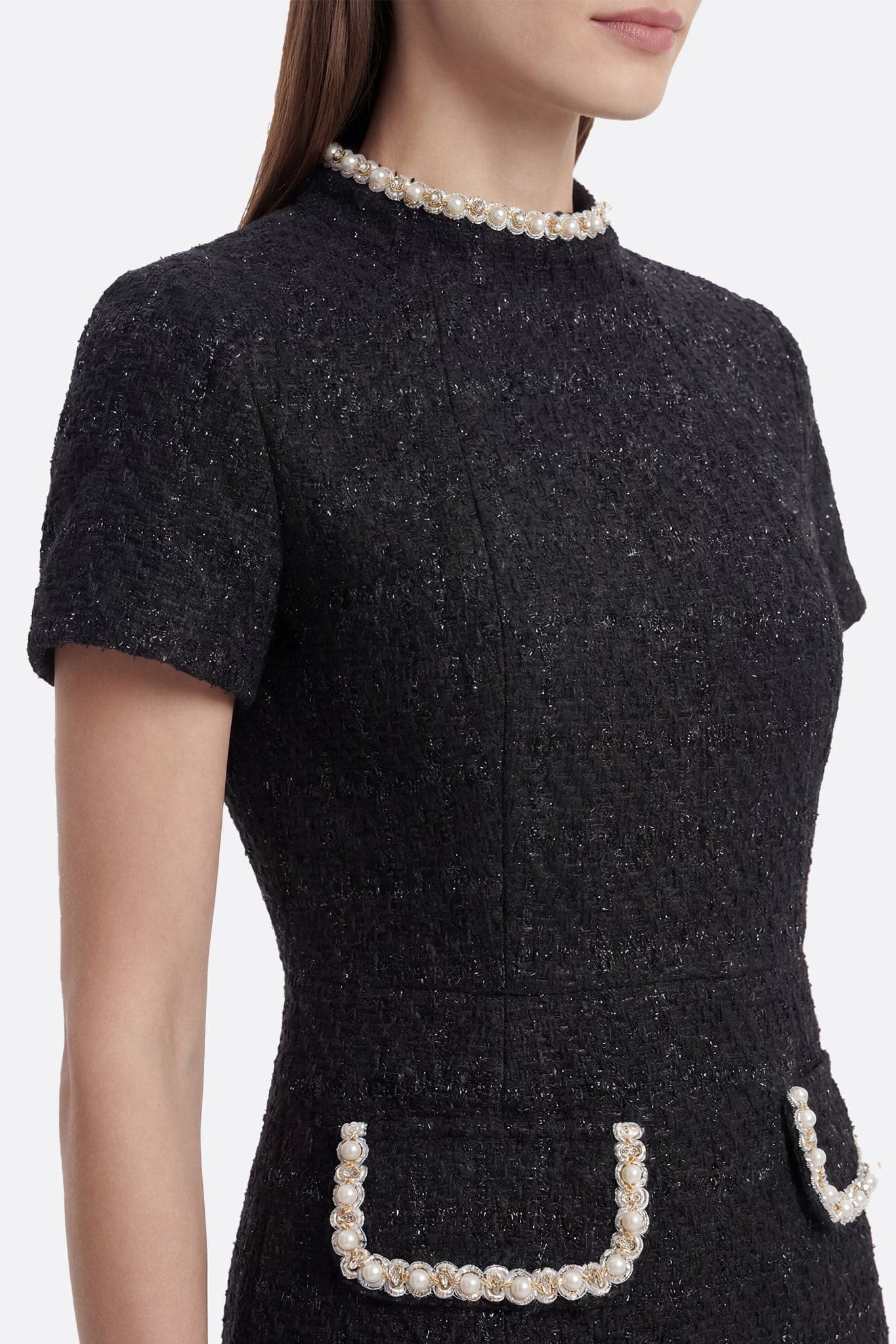 Dettaglio della schiena del vestito nero in tweed ornato di perle e cristalli, una scelta chic per un evento raffinato.