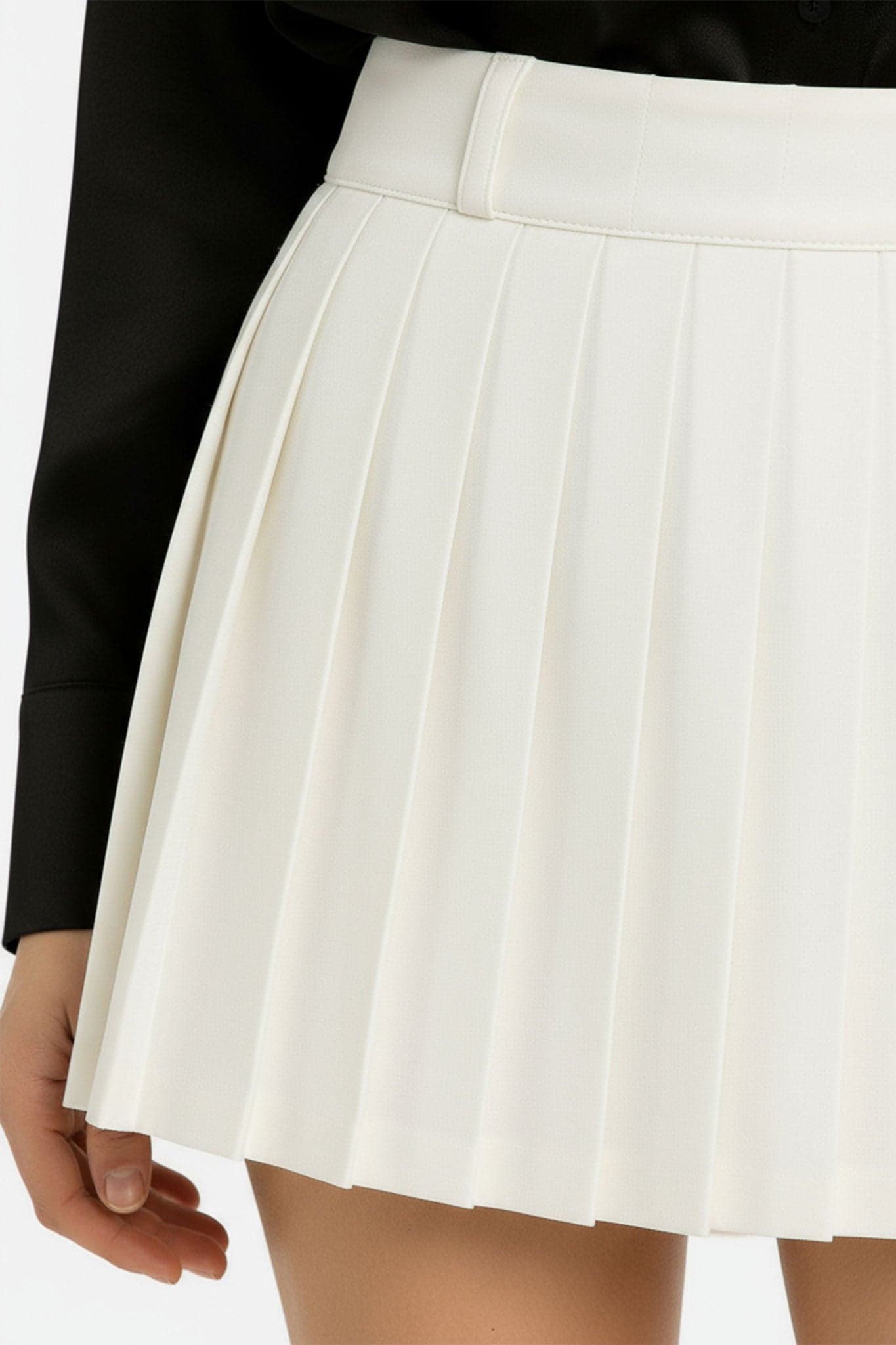 Pieghe distinte della gonna corta bianca, che sottolineano il taglio fluido e lo stile elegante per un look da giorno raffinato.