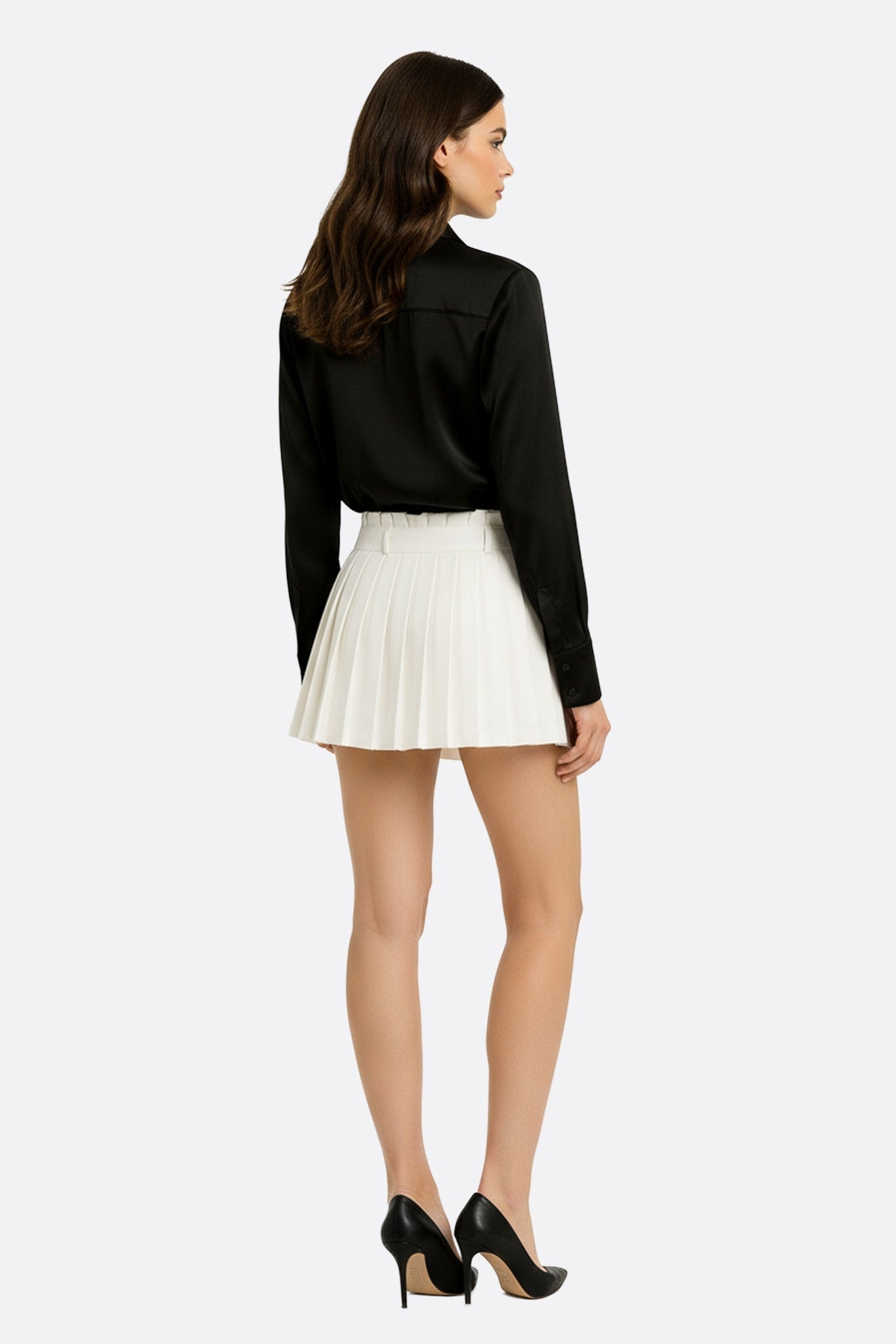 Detail of the short white pleated skirt, revealing its fluid cut and elegant allure for refined occasions.