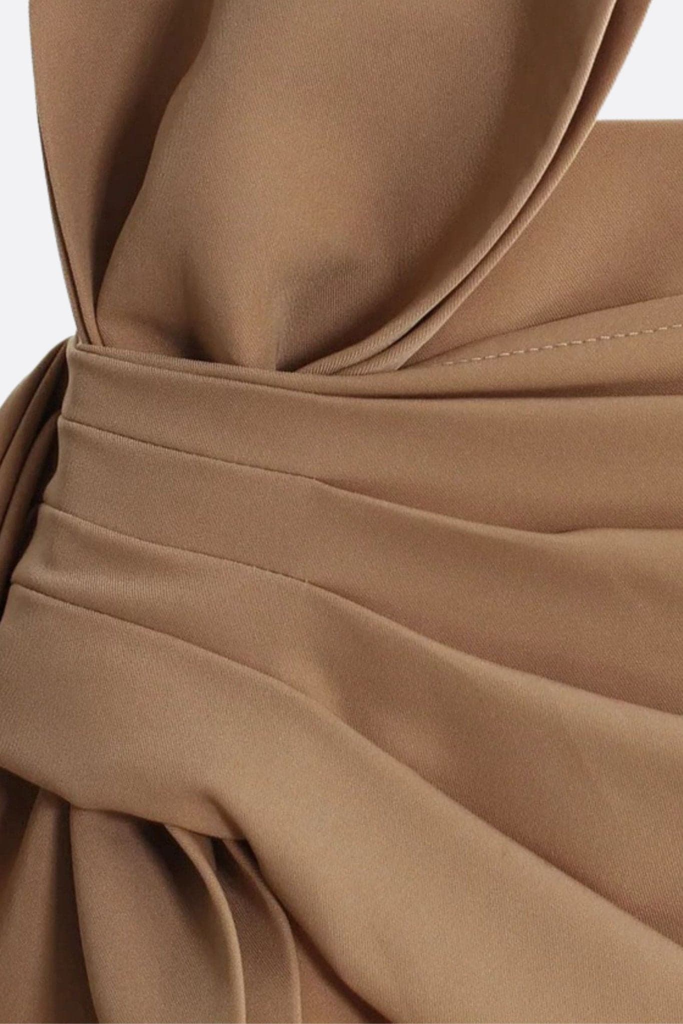 Detalle de la falda drapeada de sarga arena, ilustrando el nudo arquitectónico y el corte elegante, ideal para un estilo moderno.