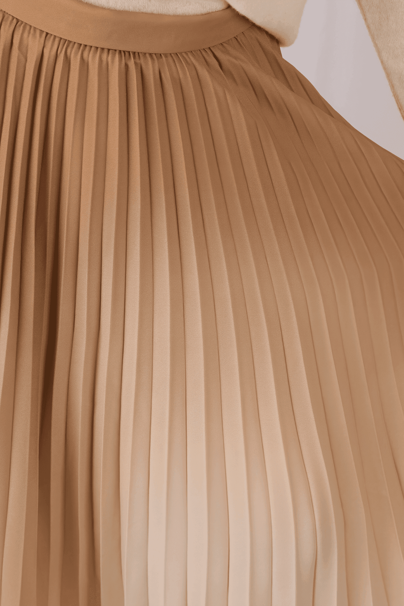 Vue détaillée de la jupe plissée longue beige, mettant en avant le dégradé délicat et son allure raffinée pour un style...