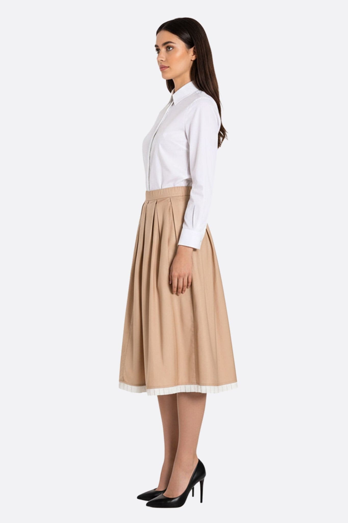 Beige pleated midi skirt seen from a three-quarter angle, highlighting its contrasting borders for a feminine and refined allure.