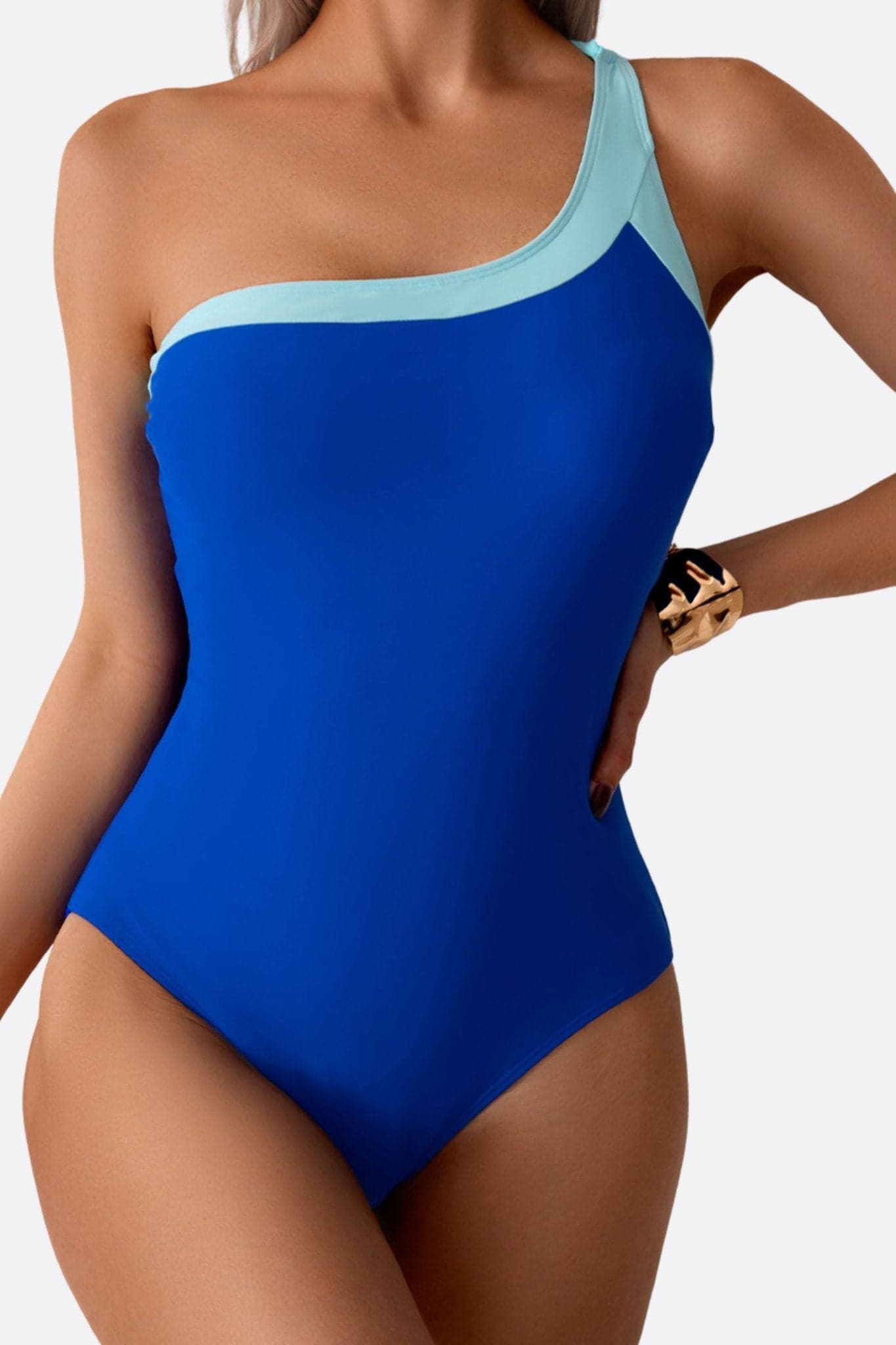 Angled detail of the blue asymmetric one-piece swimsuit, chic and sophisticated, perfect for a sunny day.