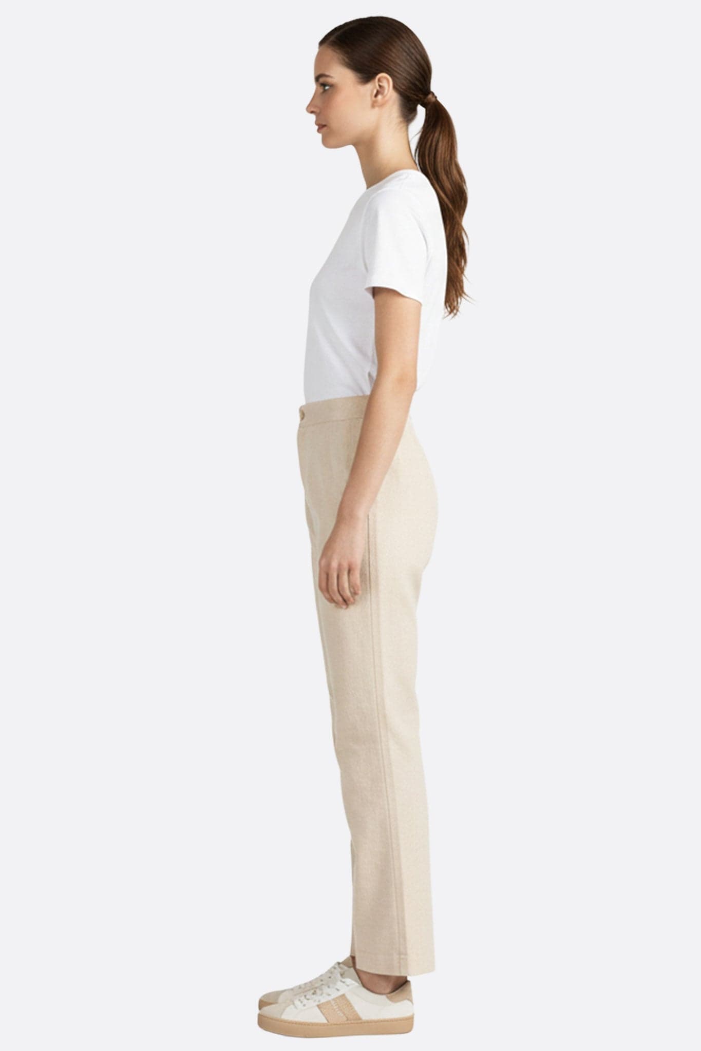 Detail of the beige high-waisted trousers, highlighting the lightweight fabric and refined allure for special occasions...