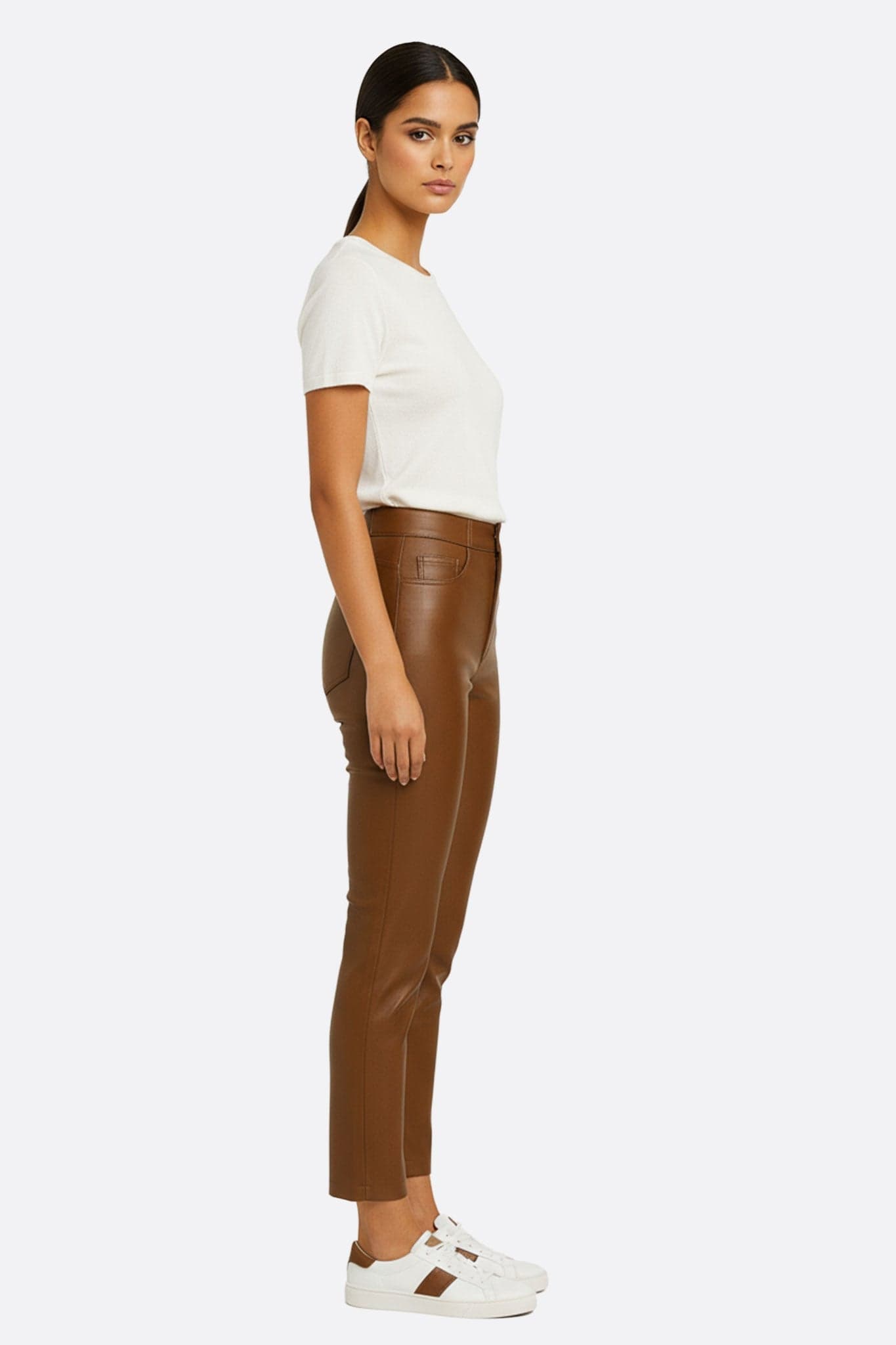 Pantalone in similpelle cammello visto a 3/4, mettendo in risalto la silhouette scolpita e l'audacia per uno stile...
