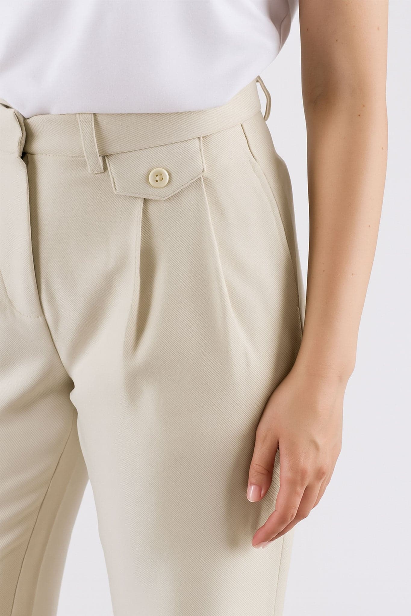 Detail of the back of the beige loose high-waisted trousers, chic and flowing for a refined style on all occasions.