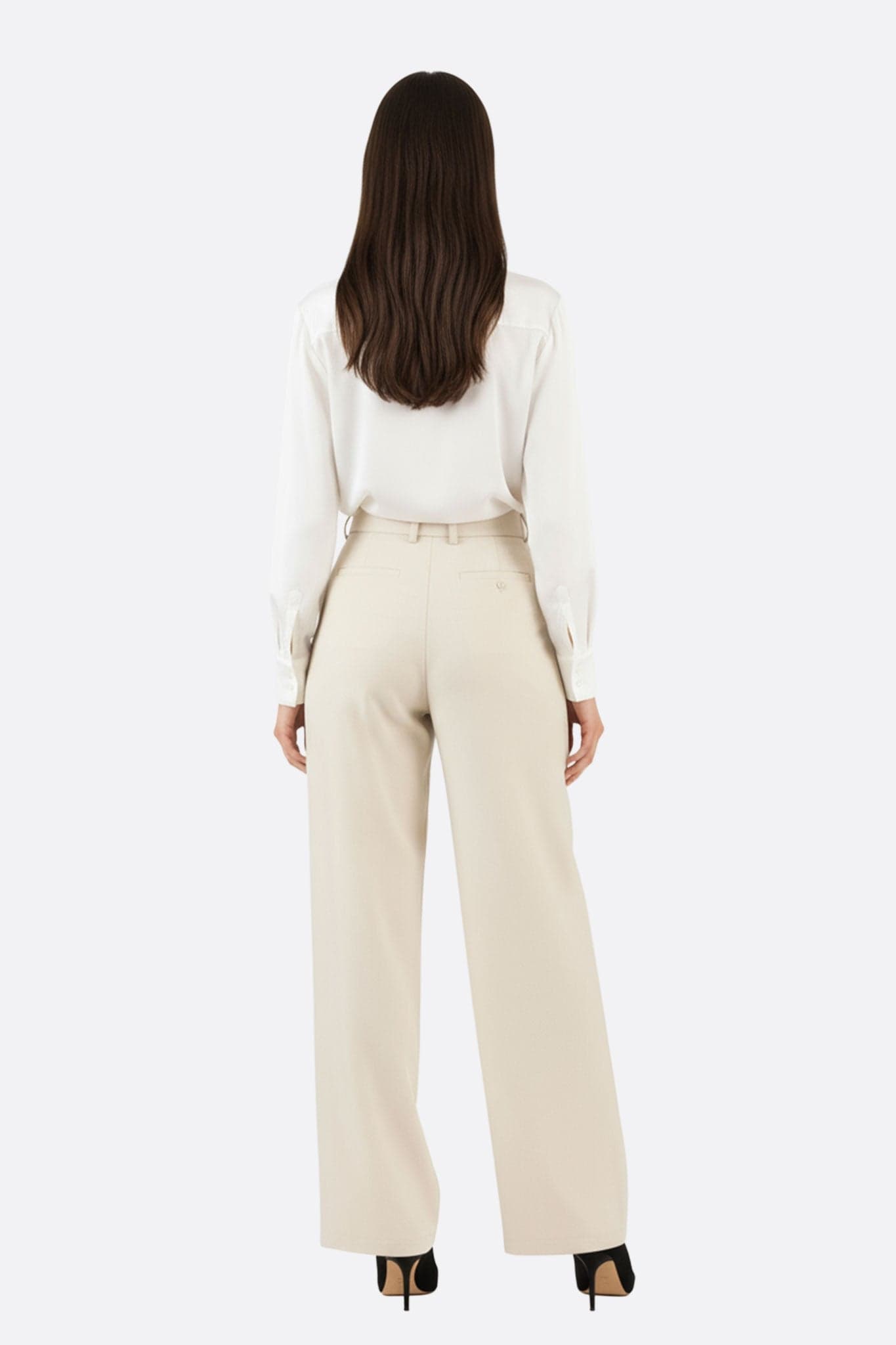 Specific detail of the loose beige high-waisted trousers, elegant and comfortable, for a sophisticated evening style.