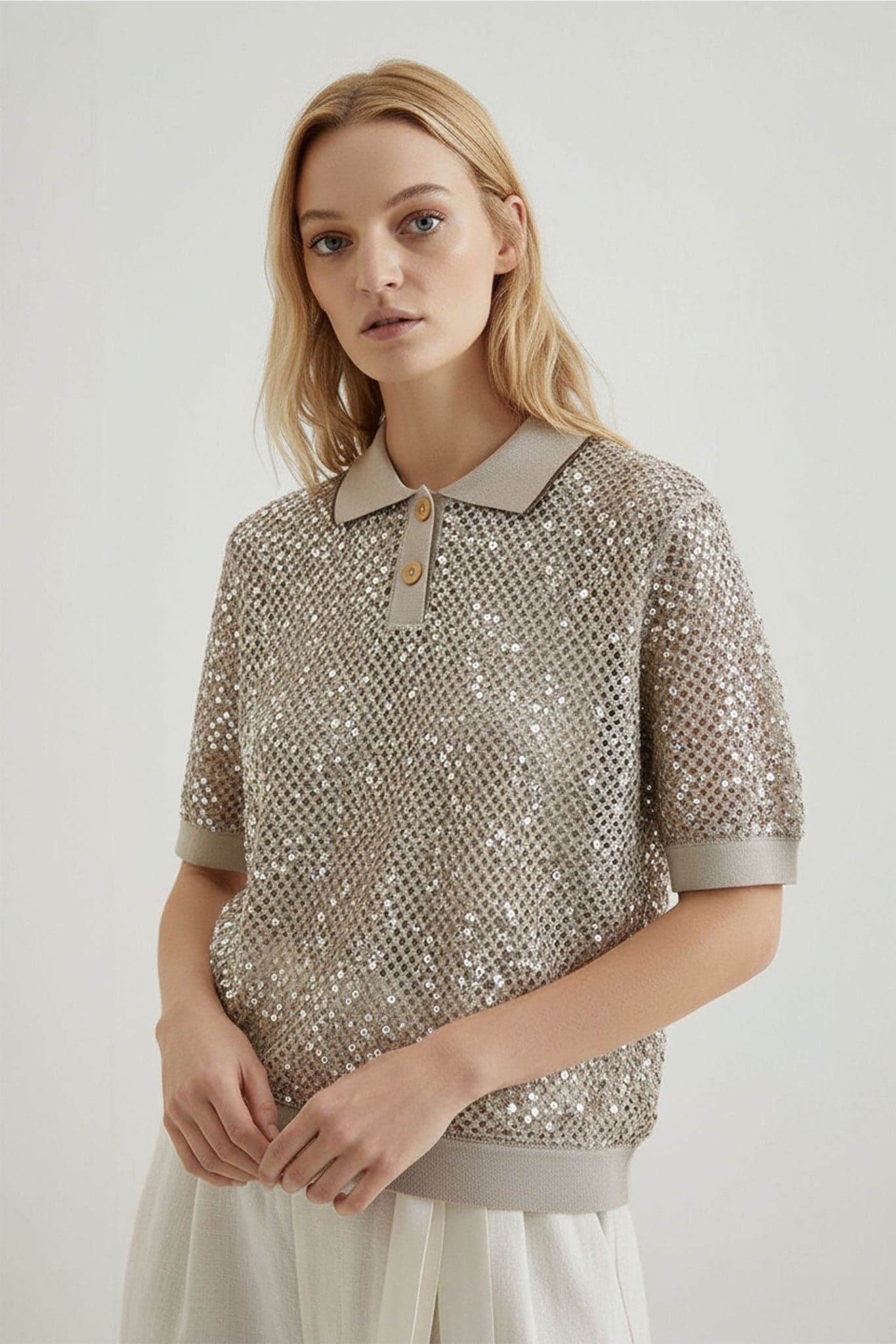 Highlighting the tone-on-tone sequins on a sand beige openwork knit polo, perfect for refined summer evenings.