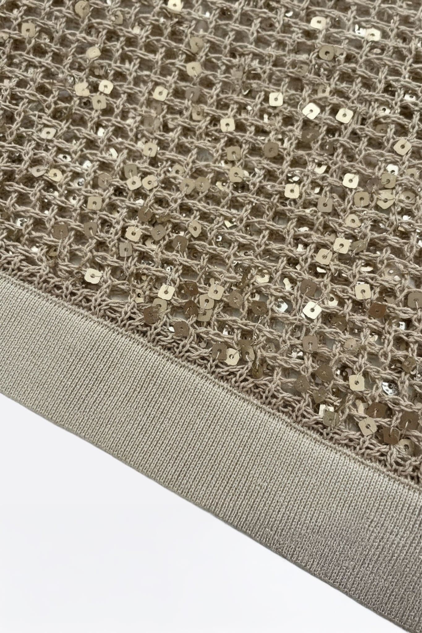 Close-up on the tone-on-tone sequins of a sand beige openwork knit polo, ideal for an elegant and refined summer style.