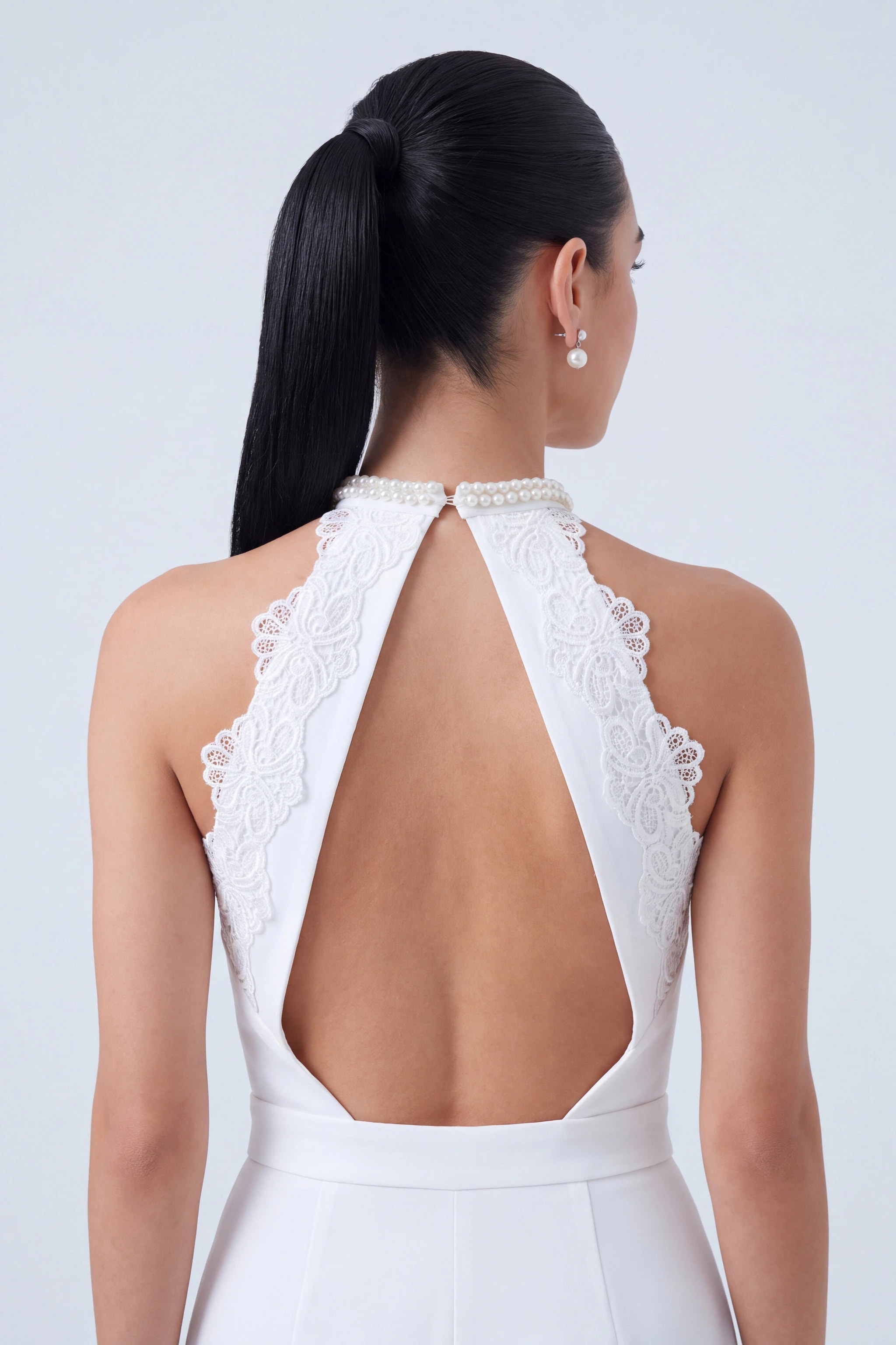 Gros plan du dos ouvert de la combinaison blanche, appliqués de guipure ton sur ton