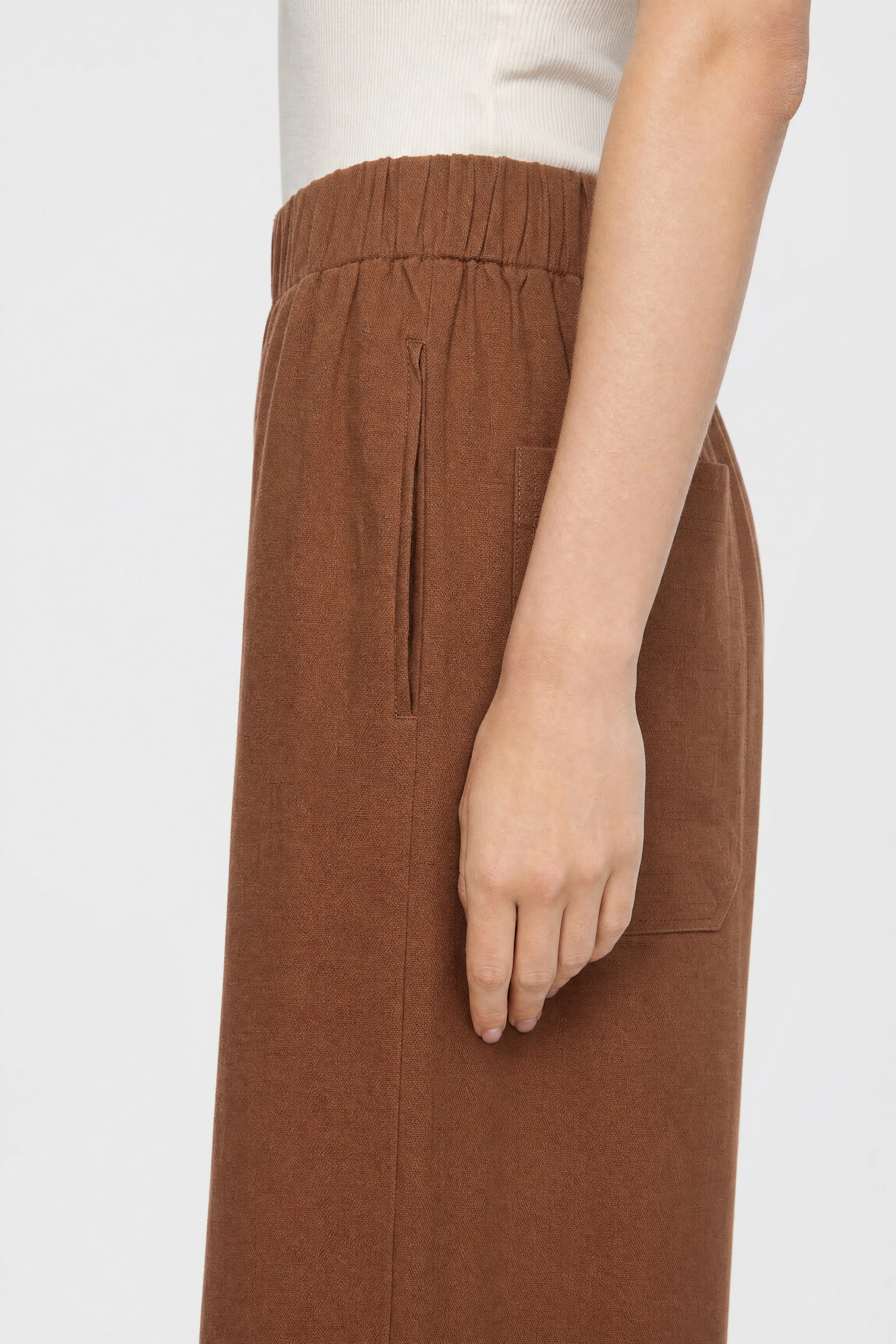 Detail of the hip of the brown linen pants: elastic waistband, side-seam pocket and patch pocket at the back