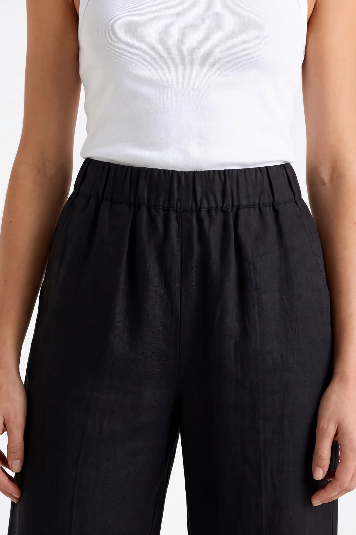 Gros plan sur la ceinture entièrement élastique du pantalon large en lin noir